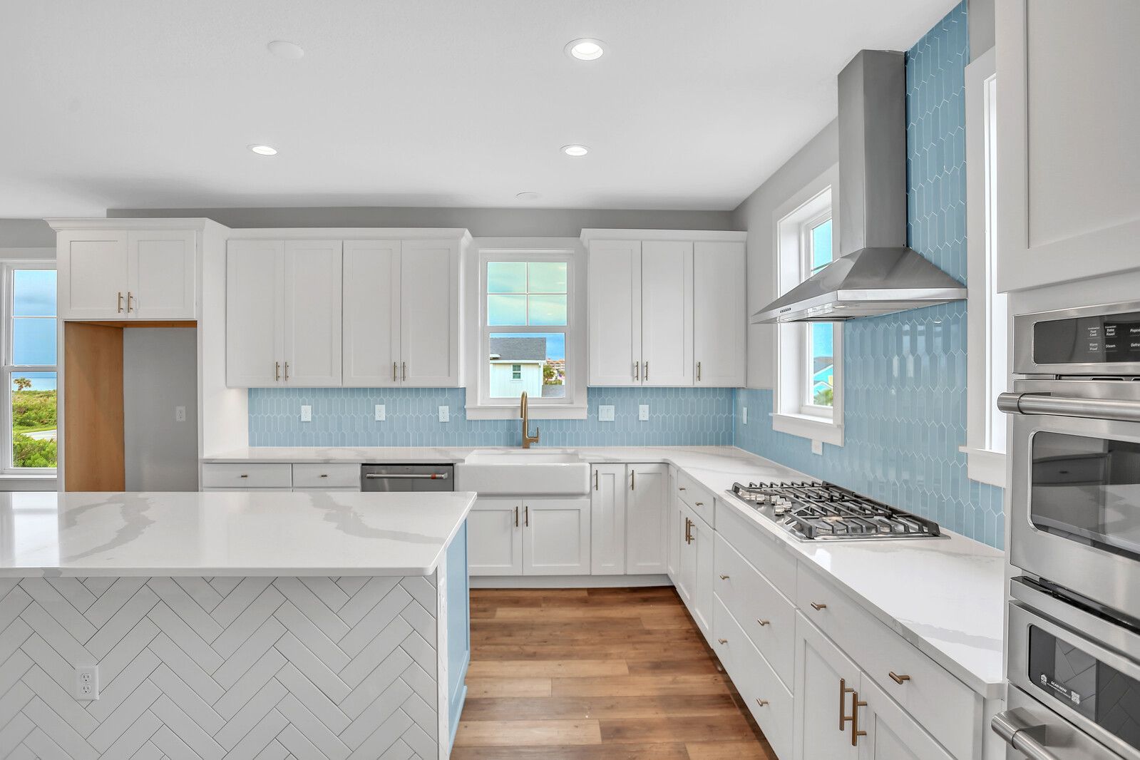 A kitchen with white cabinets , blue tiles , and stainless steel appliances.