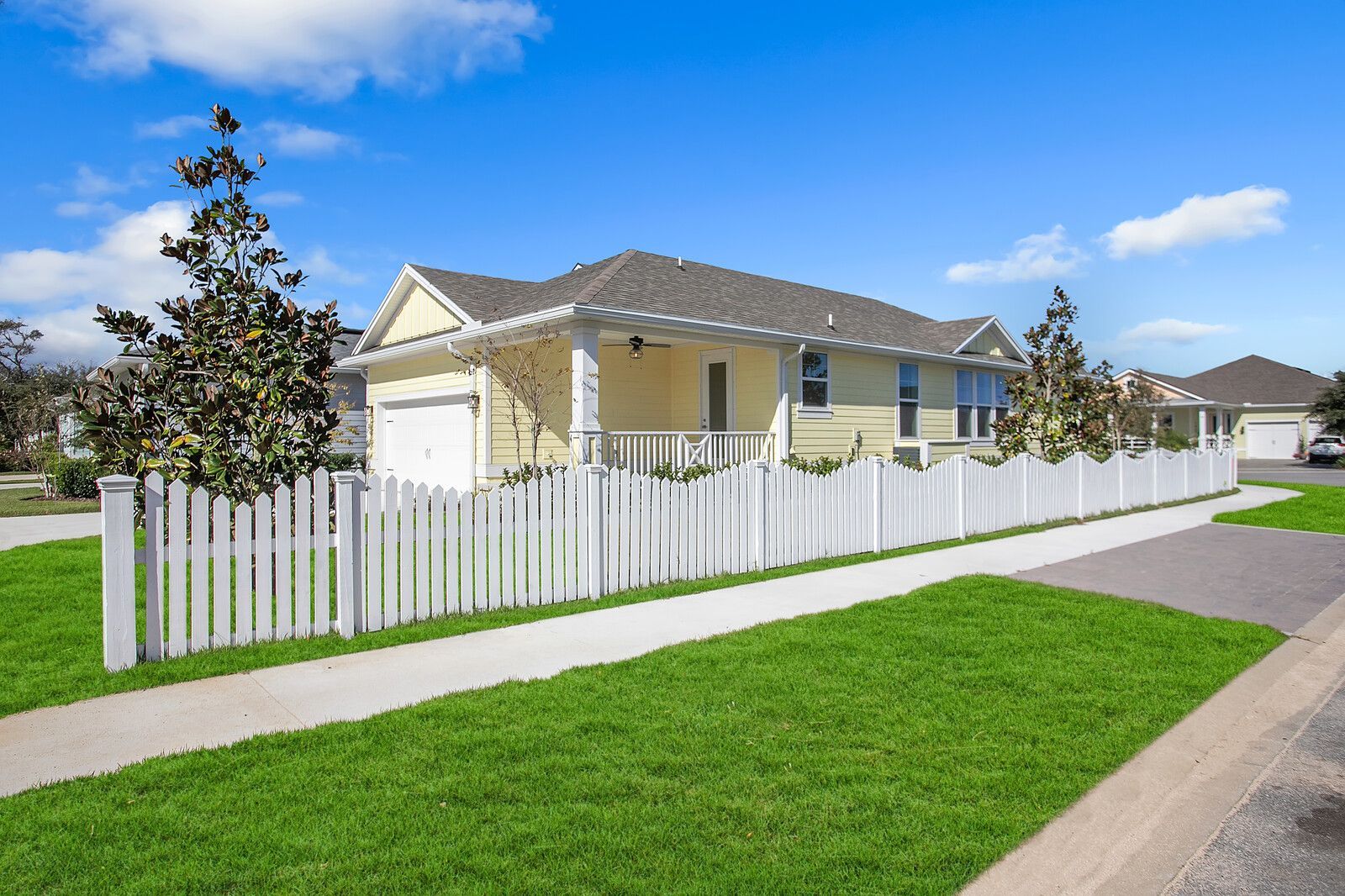 A yellow house with a white picket fence in front of it.