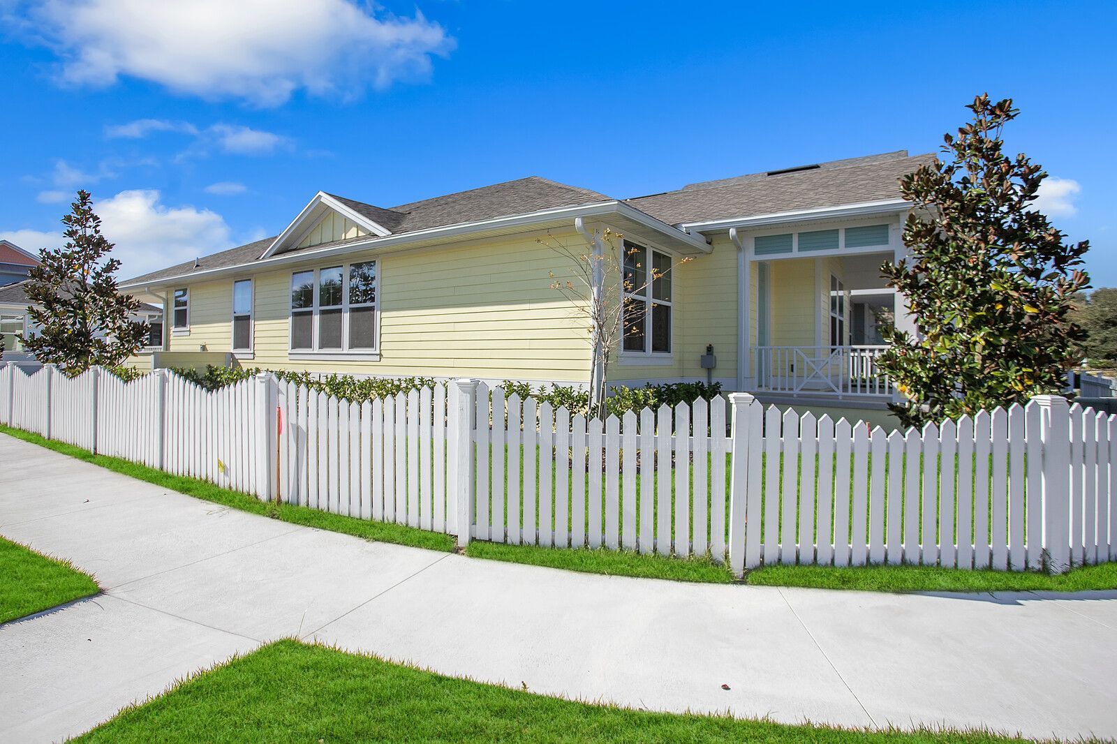 A yellow house with a white picket fence in front of it.