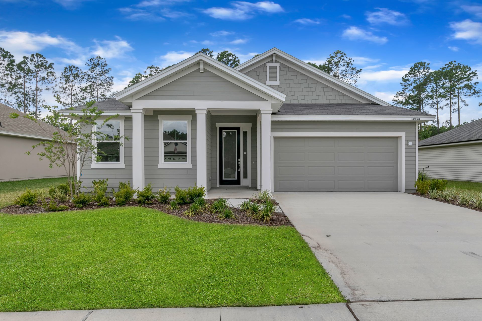 A gray and white house with a concrete driveway in front of it.