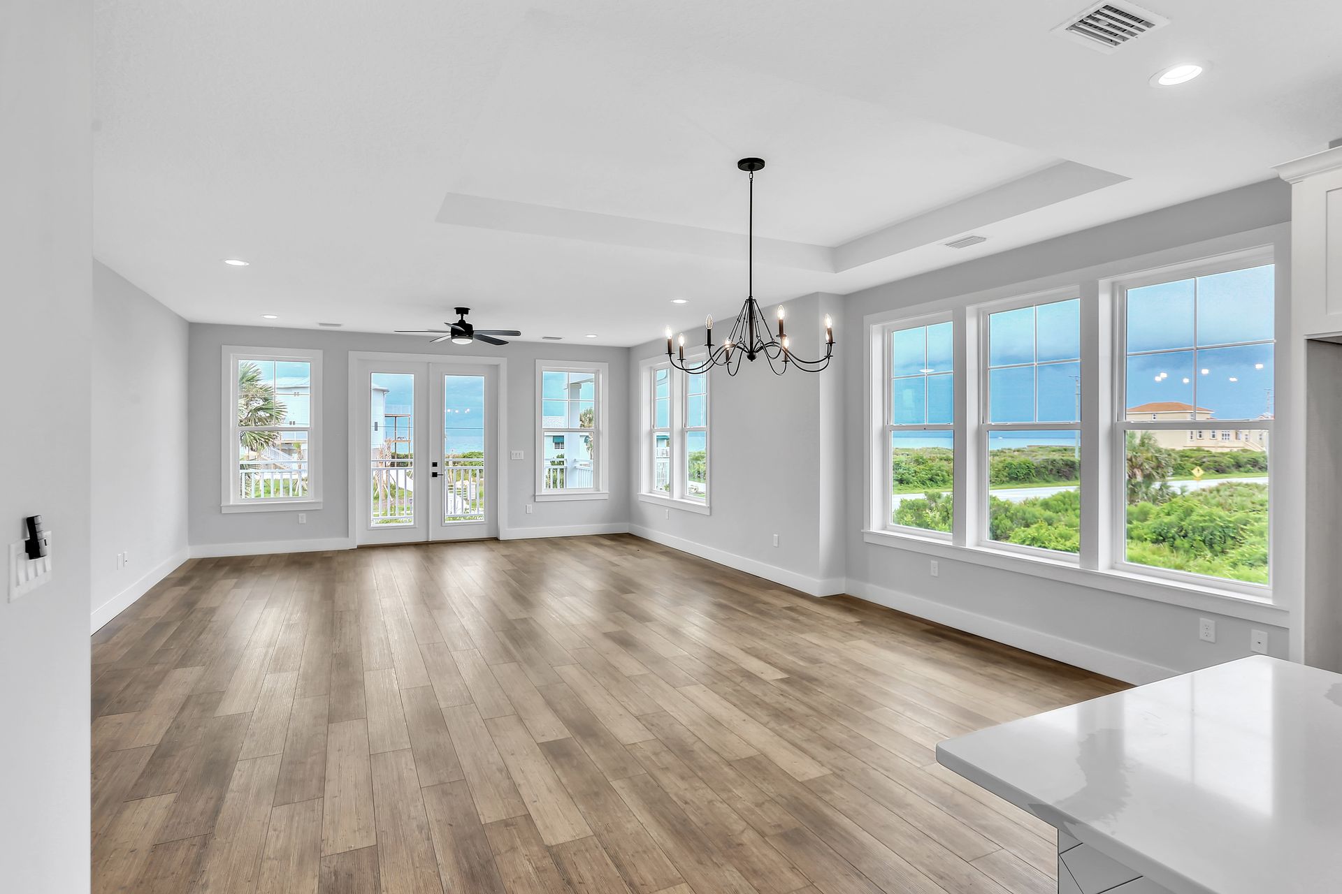 An empty living room with hardwood floors and lots of windows.