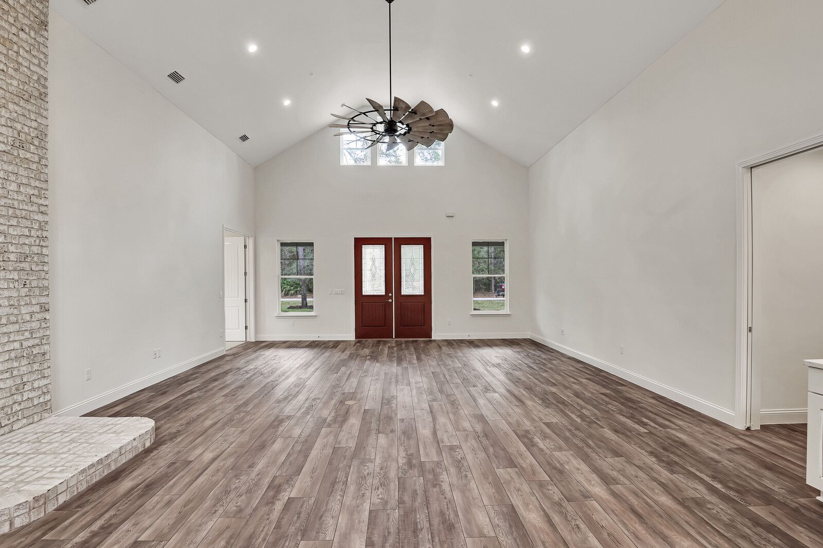 A large empty room with hardwood floors and a ceiling fan.