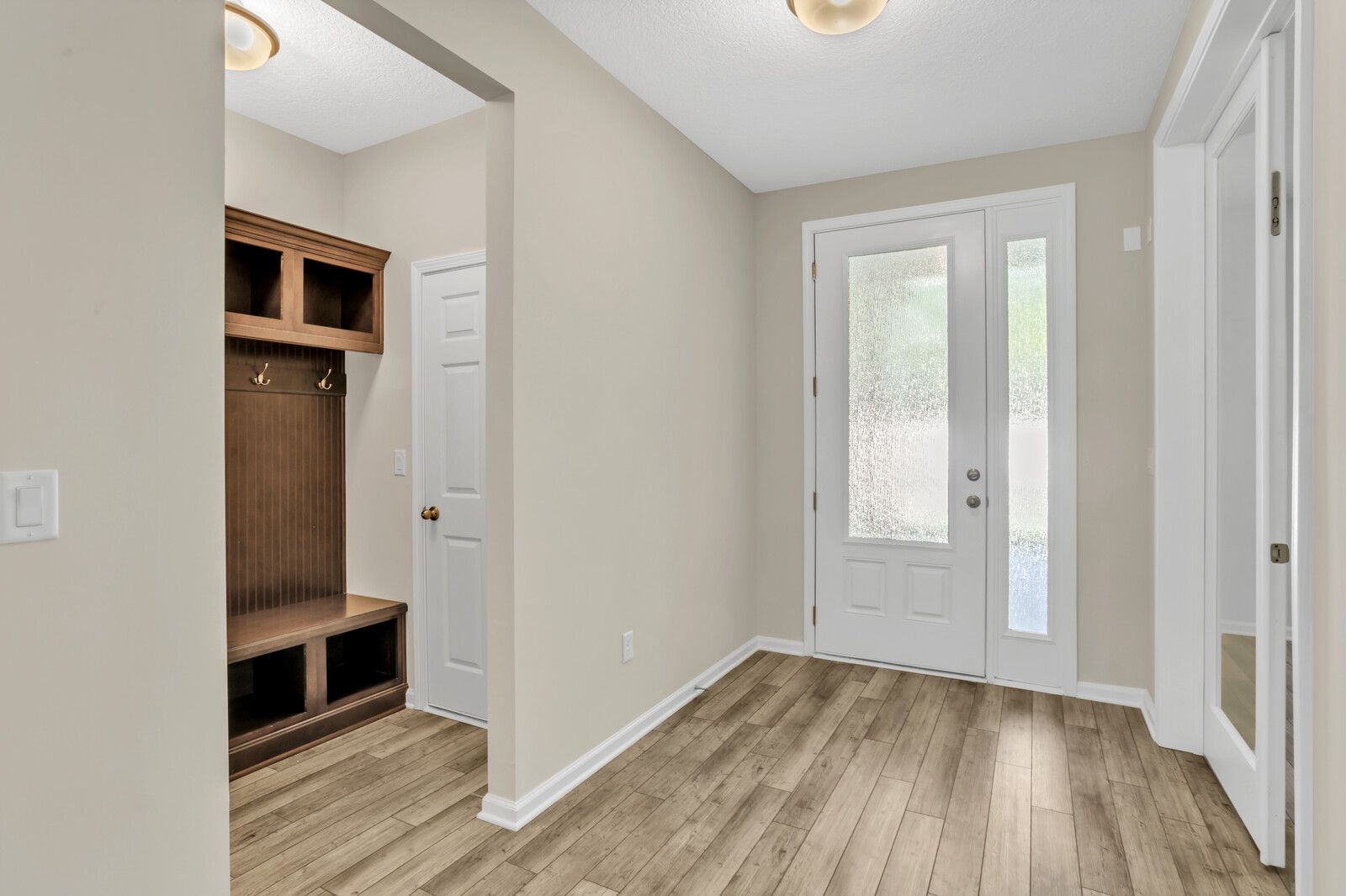 A hallway in a house with hardwood floors and a door.