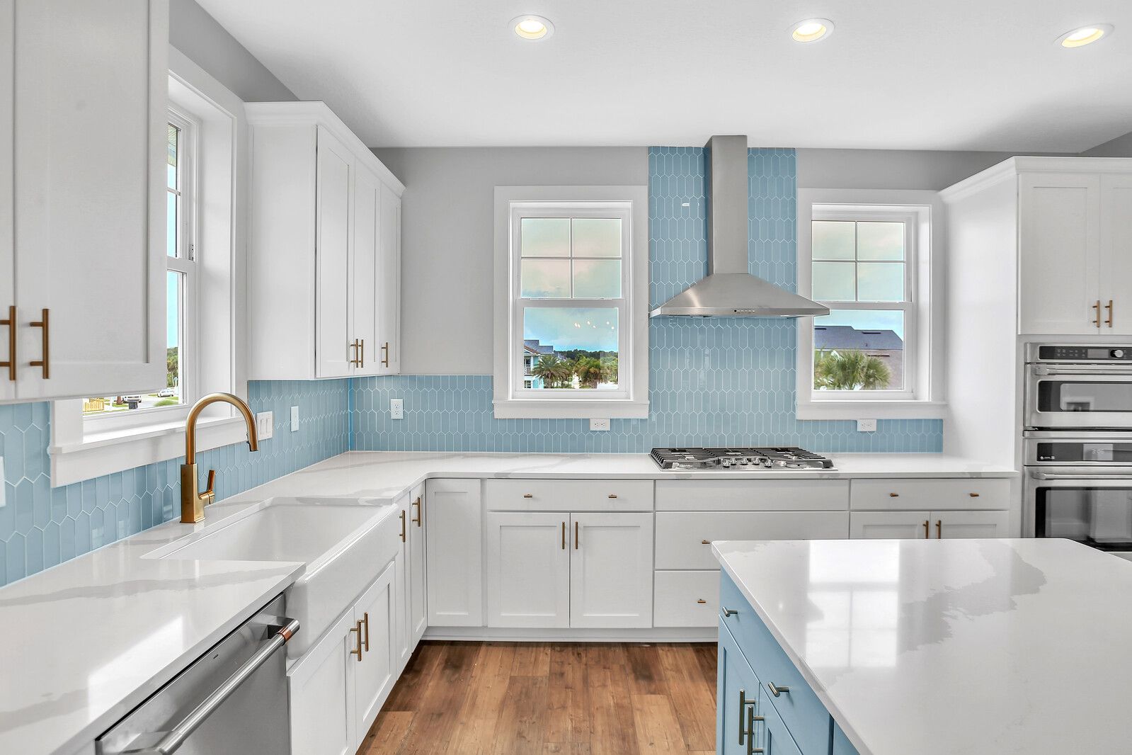 A kitchen with white cabinets , blue tiles , stainless steel appliances and a large island.