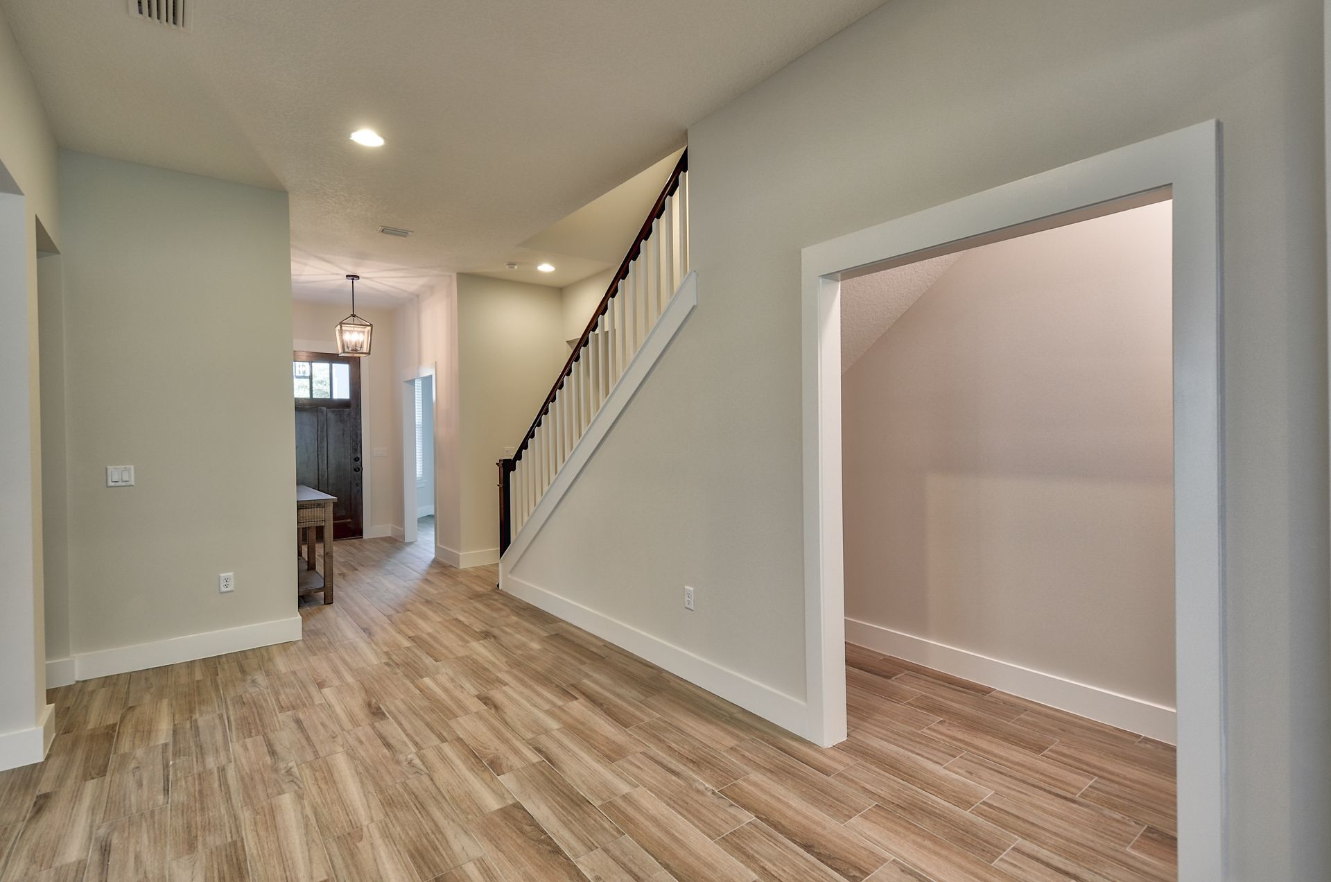A hallway with hardwood floors and stairs in a house.