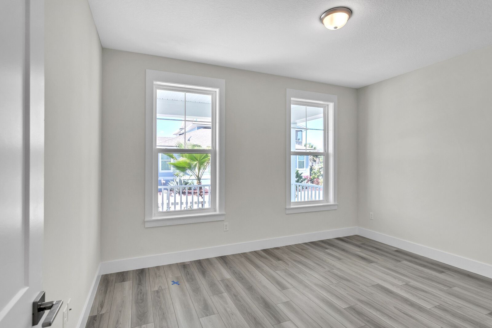 An empty bedroom with hardwood floors and two windows.