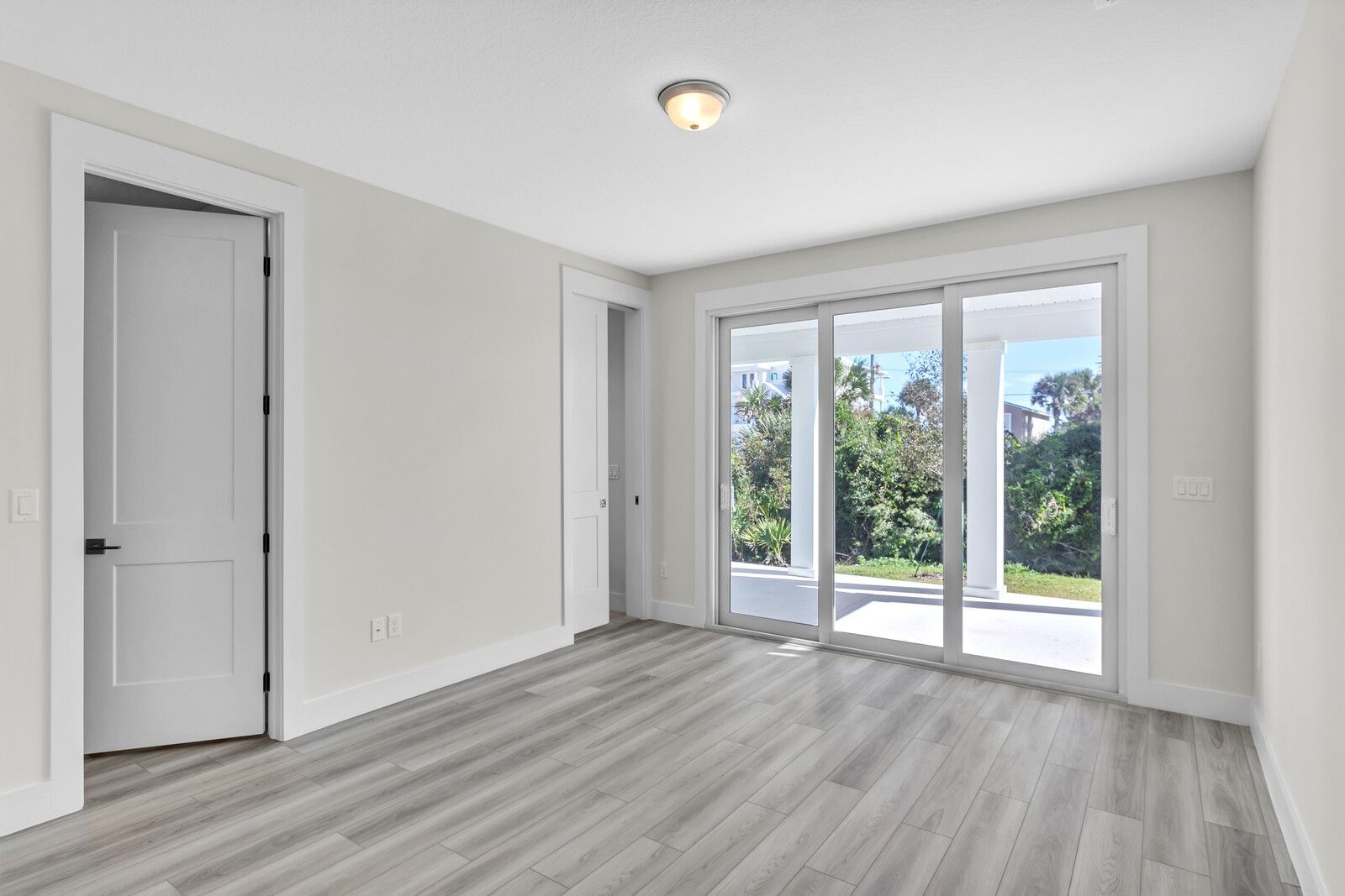 An empty room with hardwood floors and sliding glass doors.