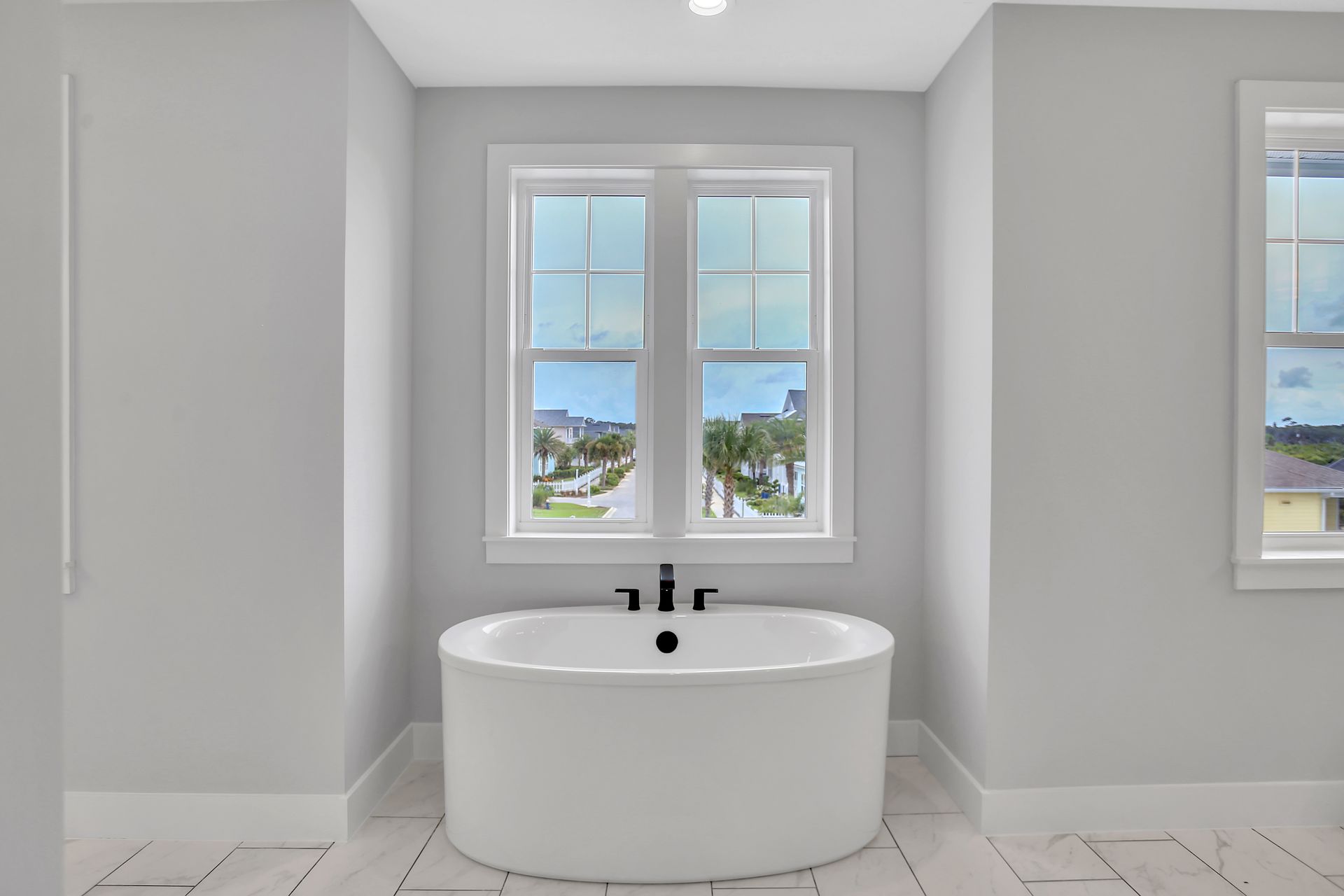 A bathroom with a bathtub and two windows.