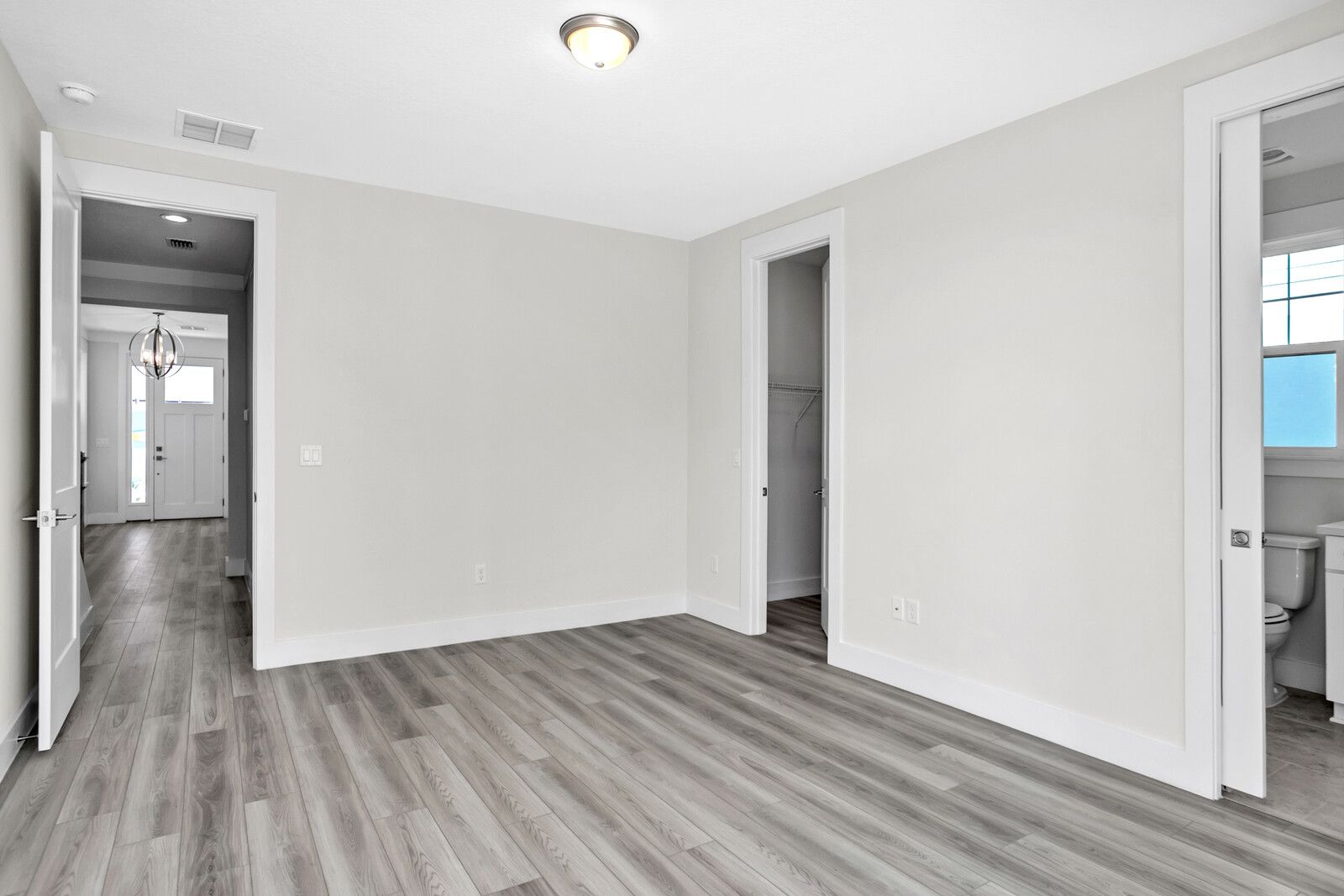 An empty room with hardwood floors and white walls in a house.