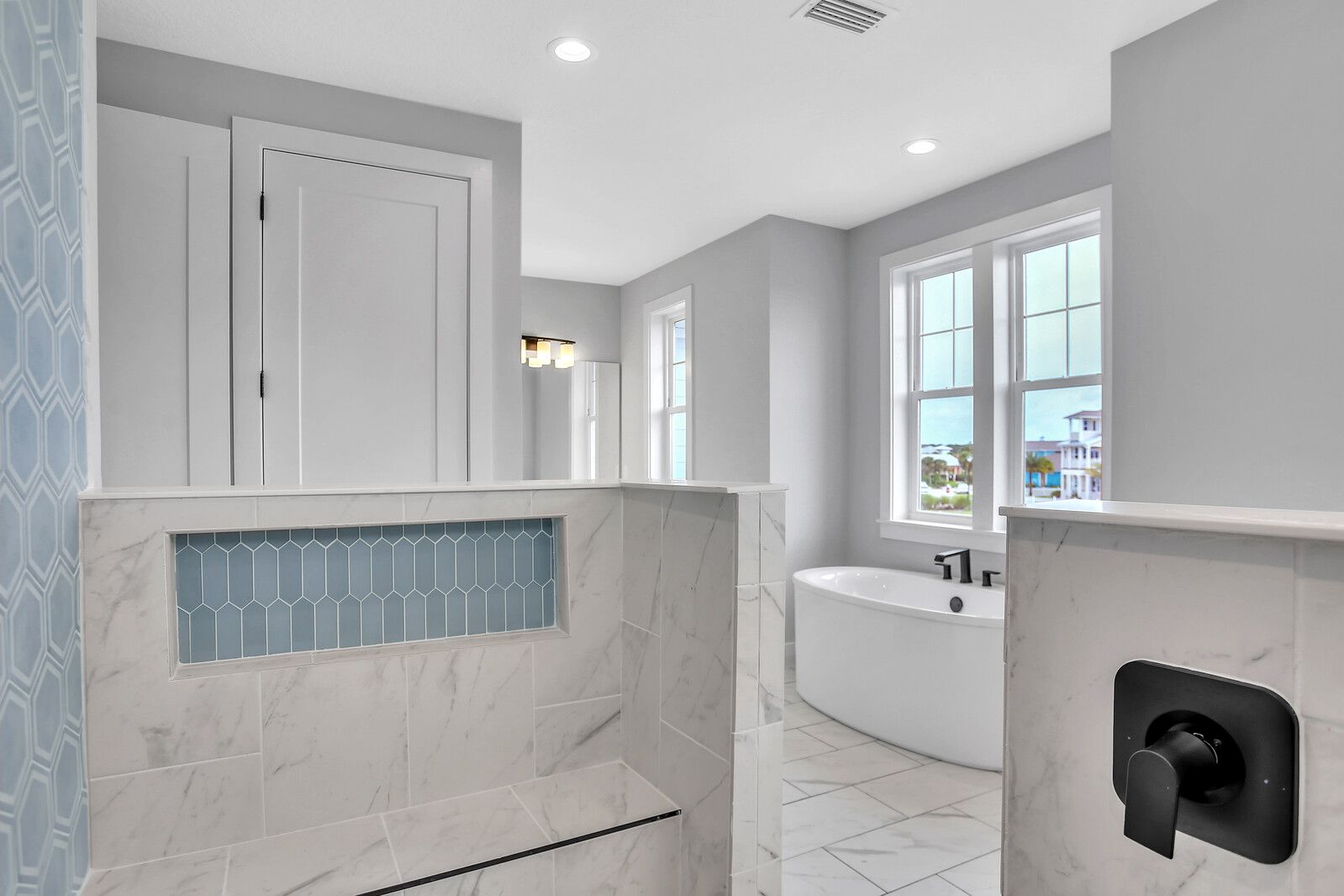 A bathroom with a tub , shower , mirror and window.