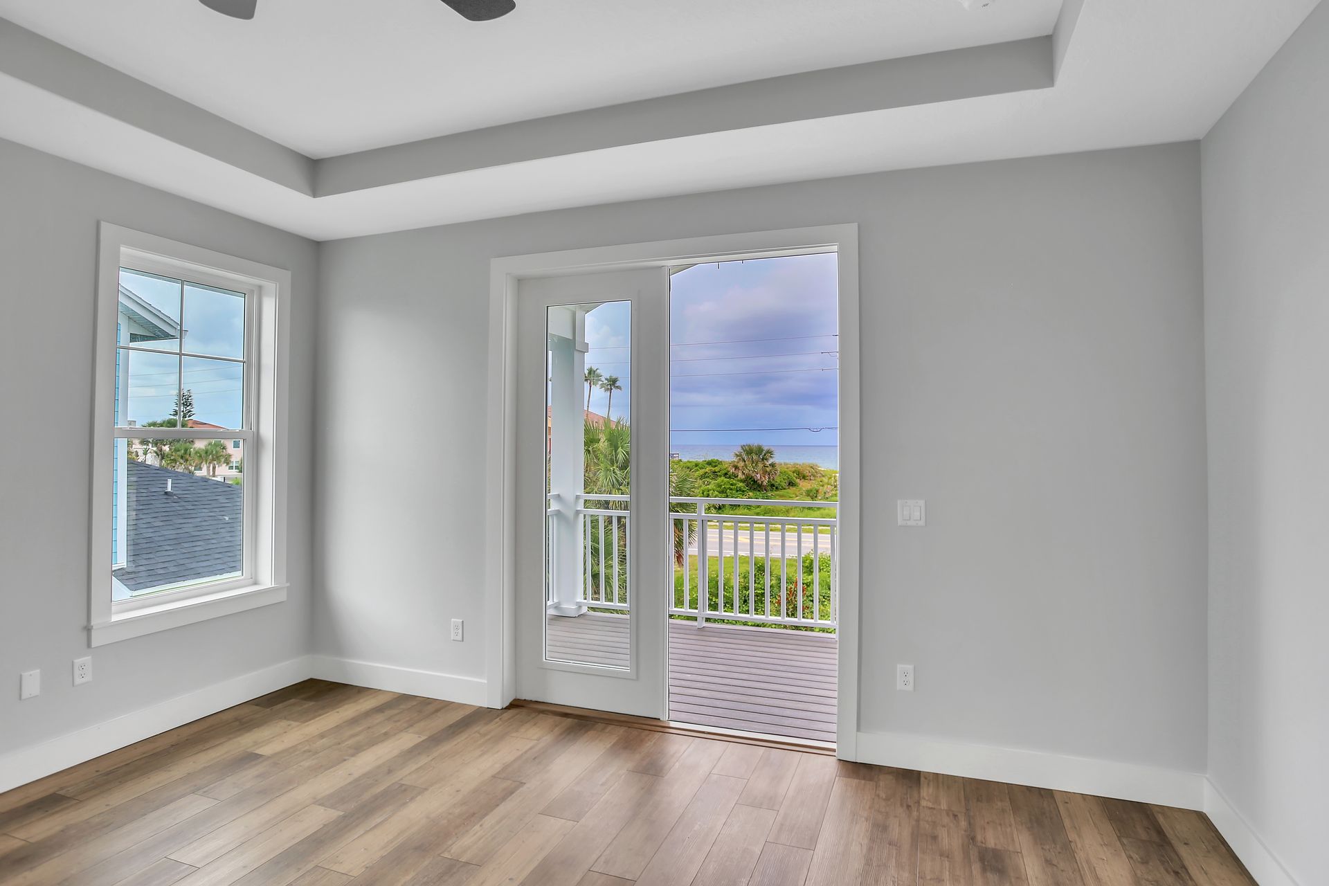 An empty room with hardwood floors and sliding glass doors leading to a balcony.