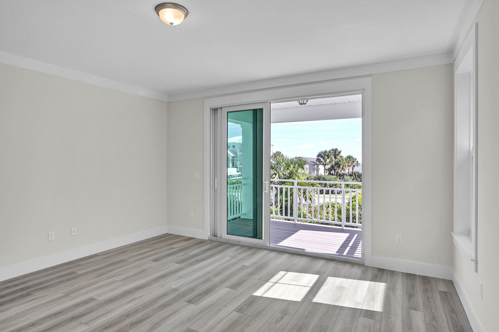 An empty room with a sliding glass door leading to a balcony.