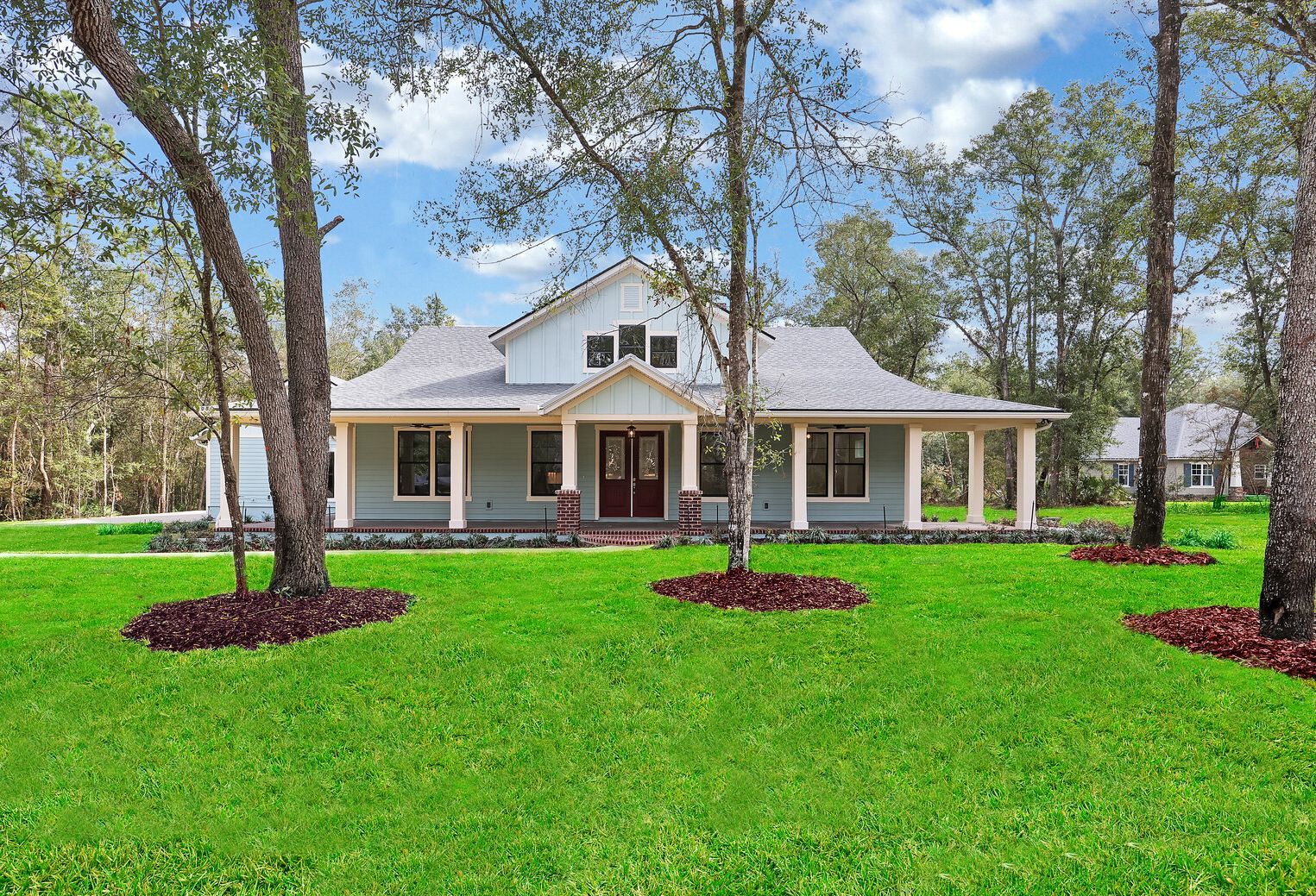 A large house with a large lawn in front of it surrounded by trees.