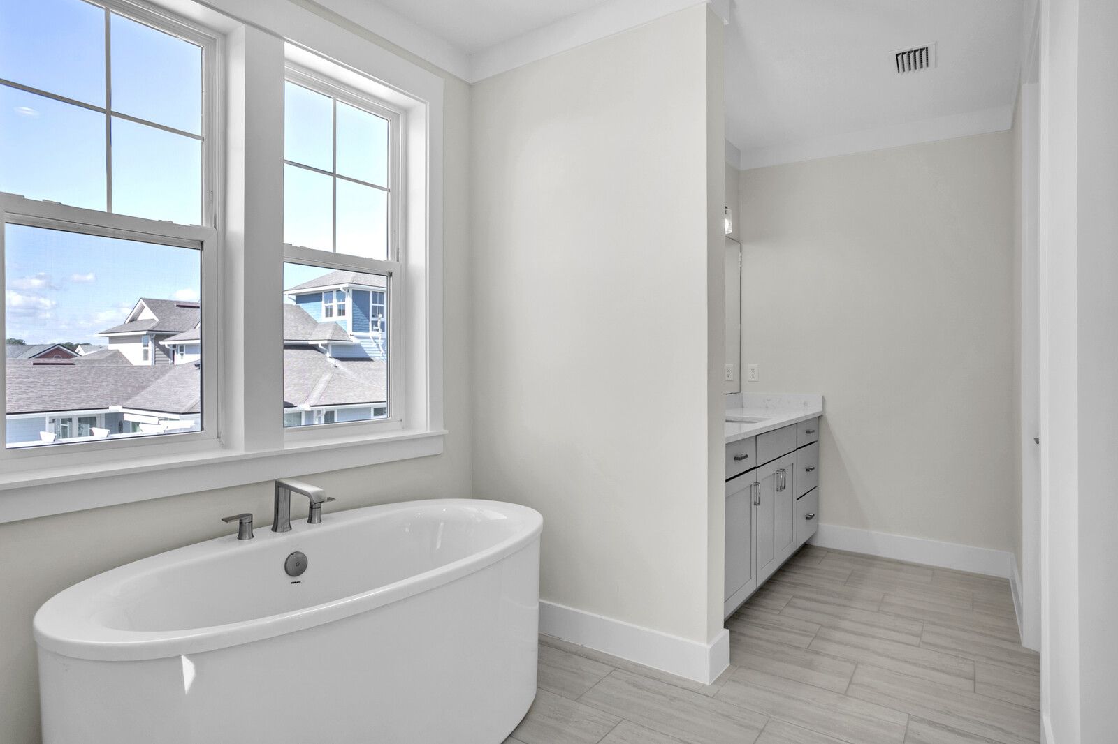 A bathroom with a bathtub and two windows.