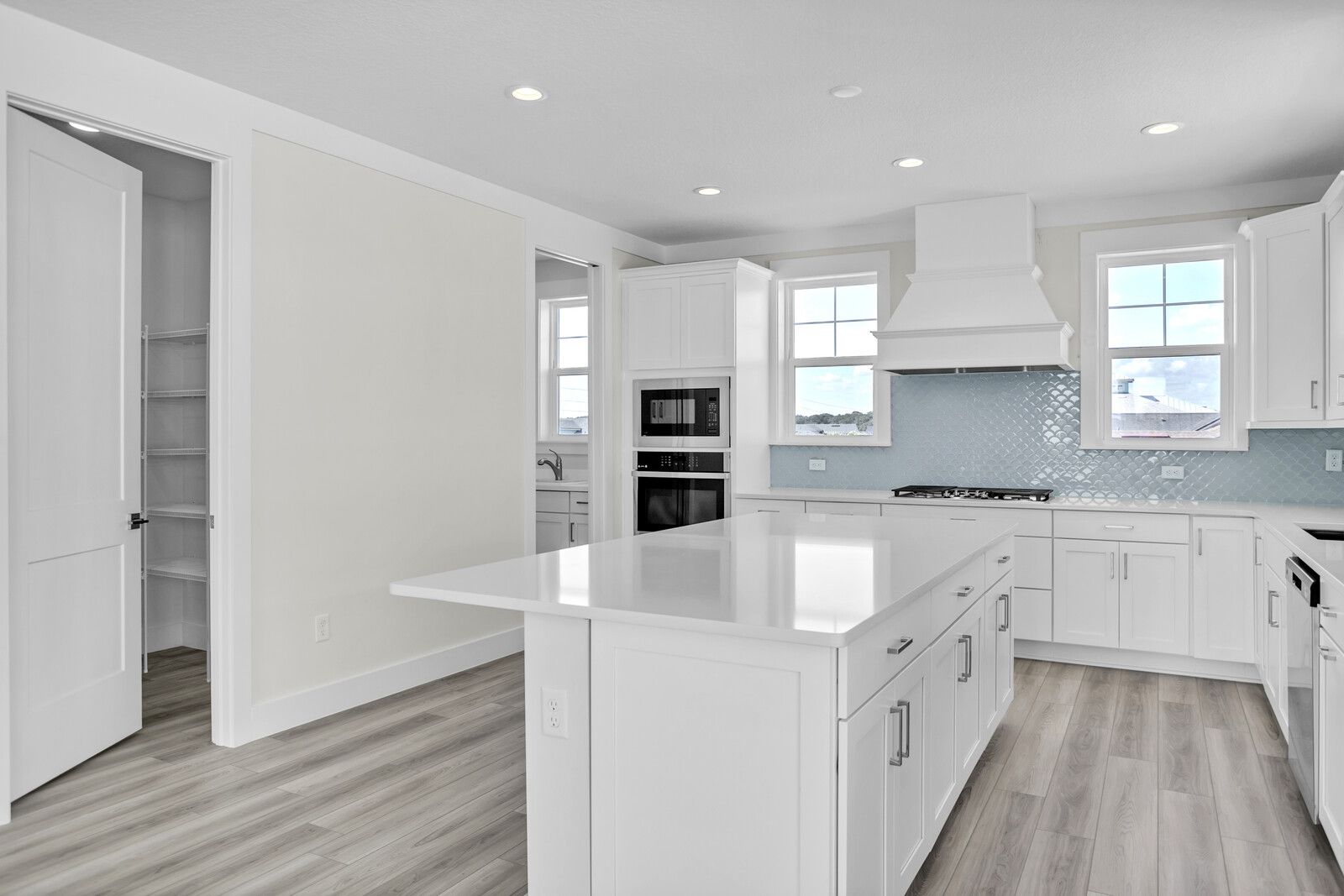 A kitchen with white cabinets and a large island in the middle.