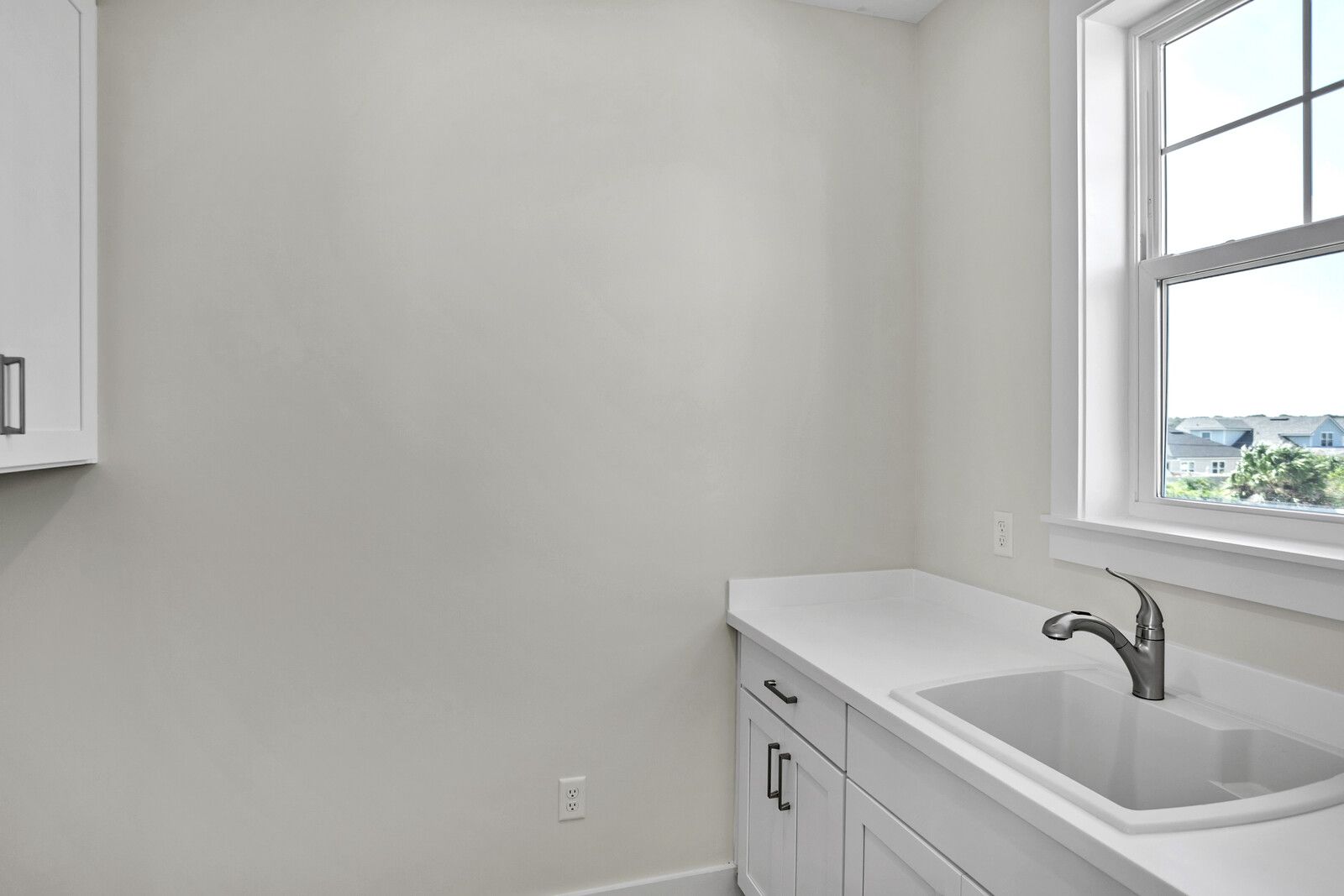 A laundry room with a sink and a window.