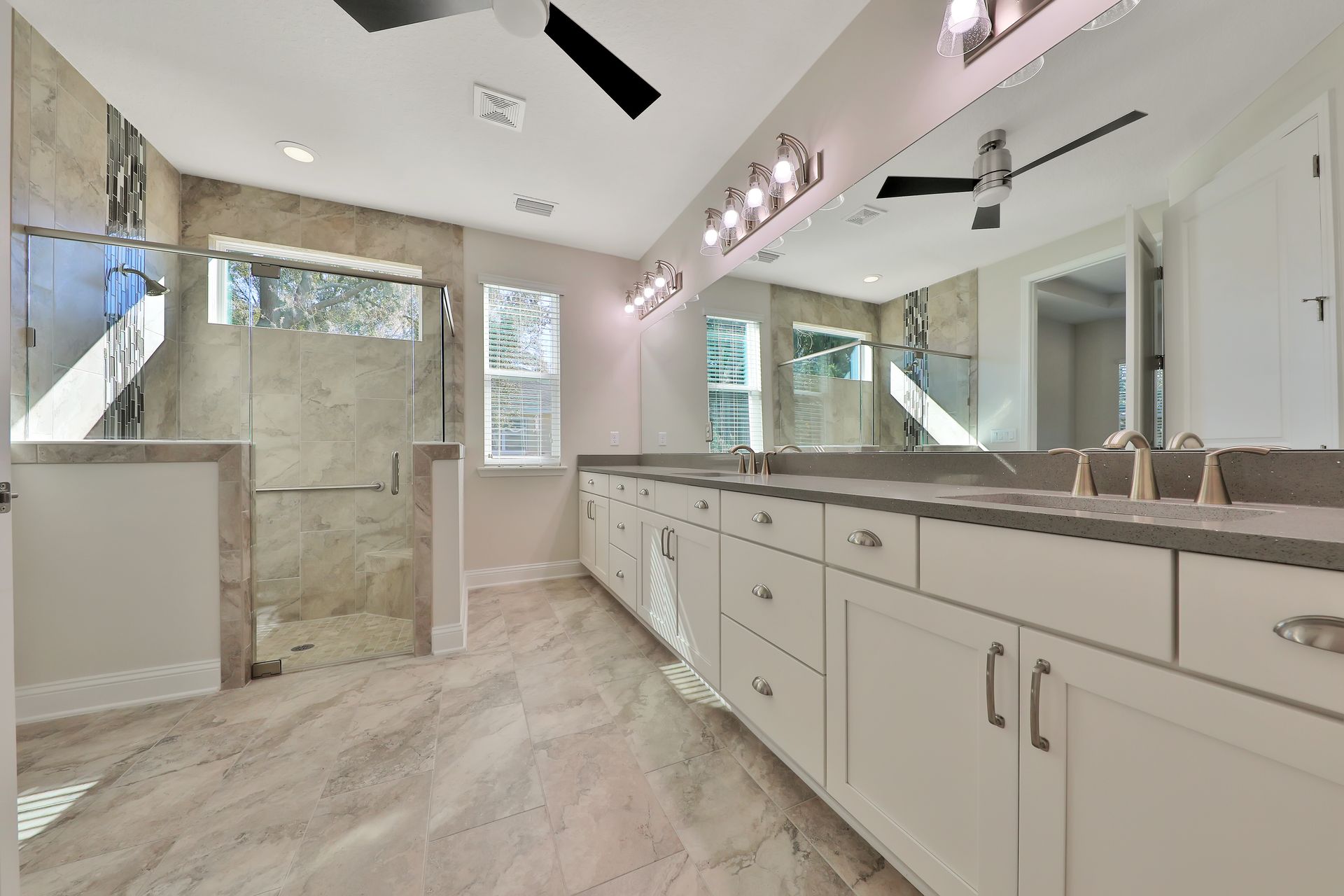 A bathroom with two sinks and a walk in shower.
