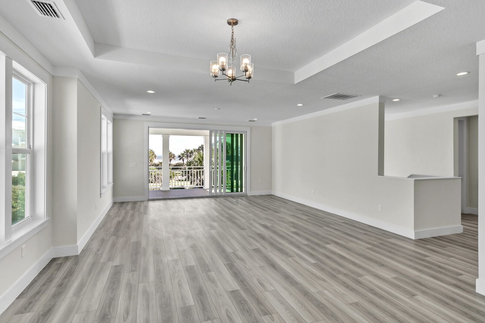 An empty living room with hardwood floors and a chandelier.