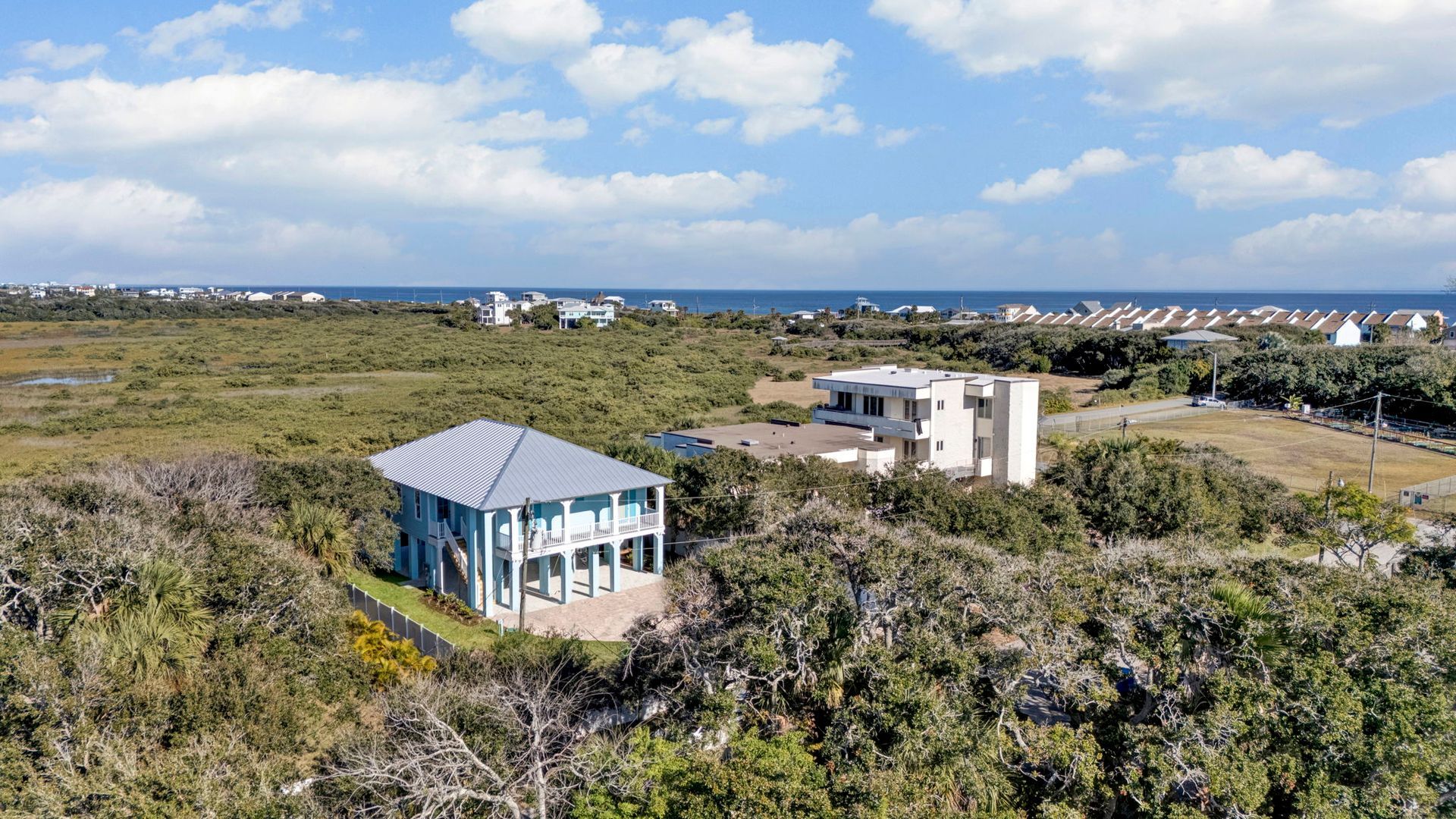 Coastal aerial view of a custom Encore home with dense greenery under clear sky