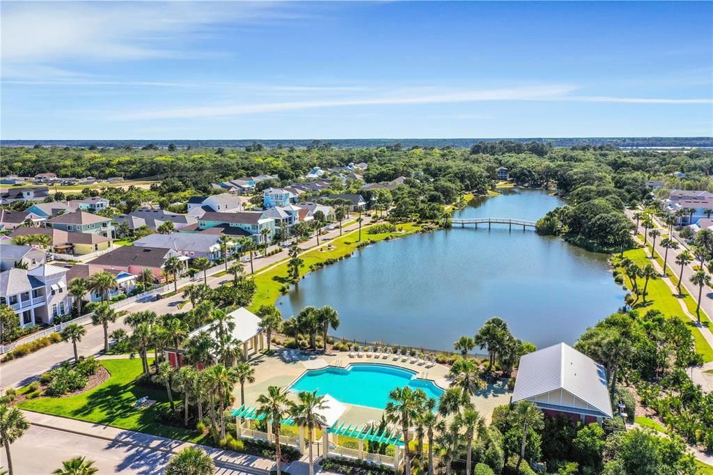 An aerial view of a lake surrounded by trees and houses in a residential area.