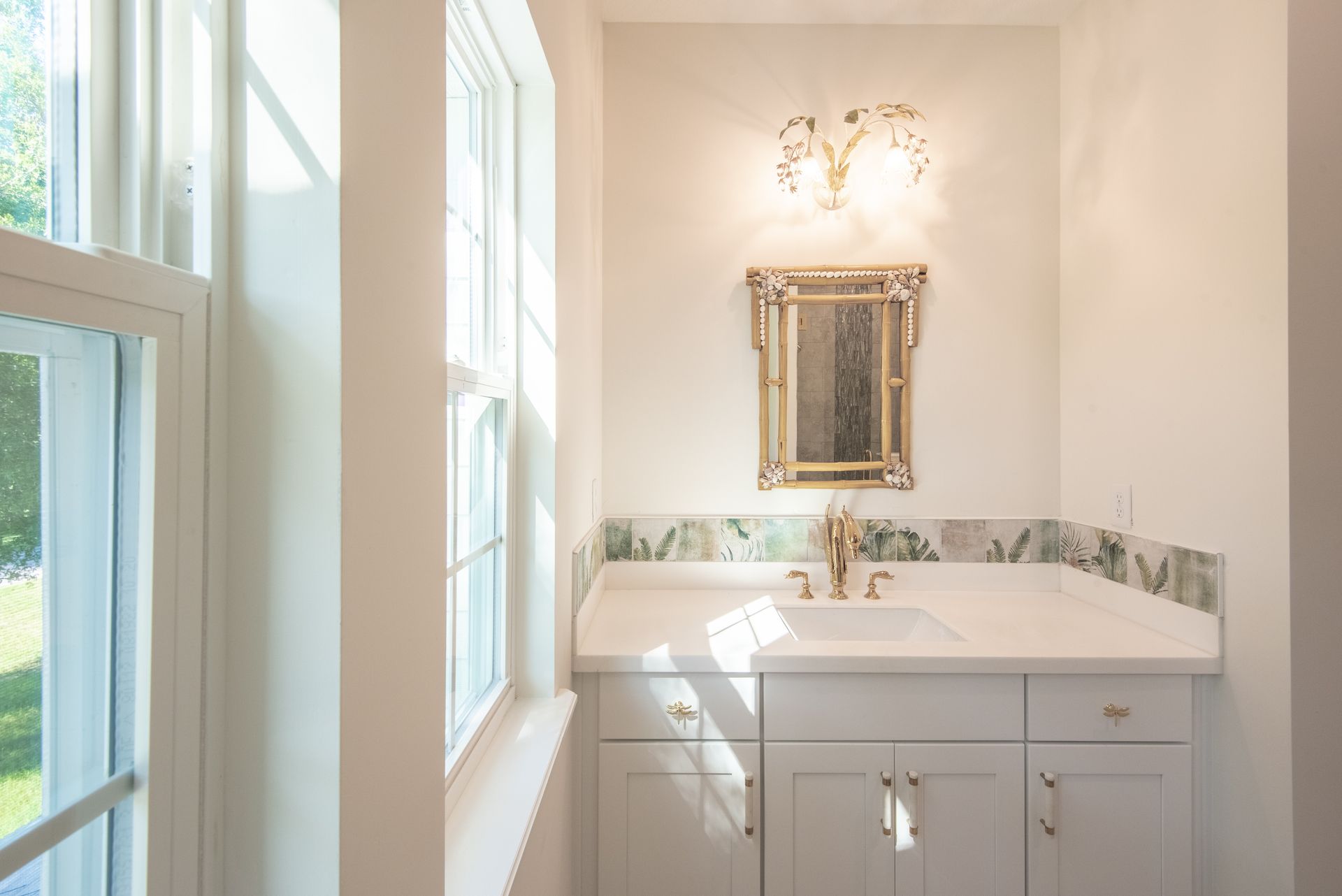 A bathroom with a sink , mirror and window.
