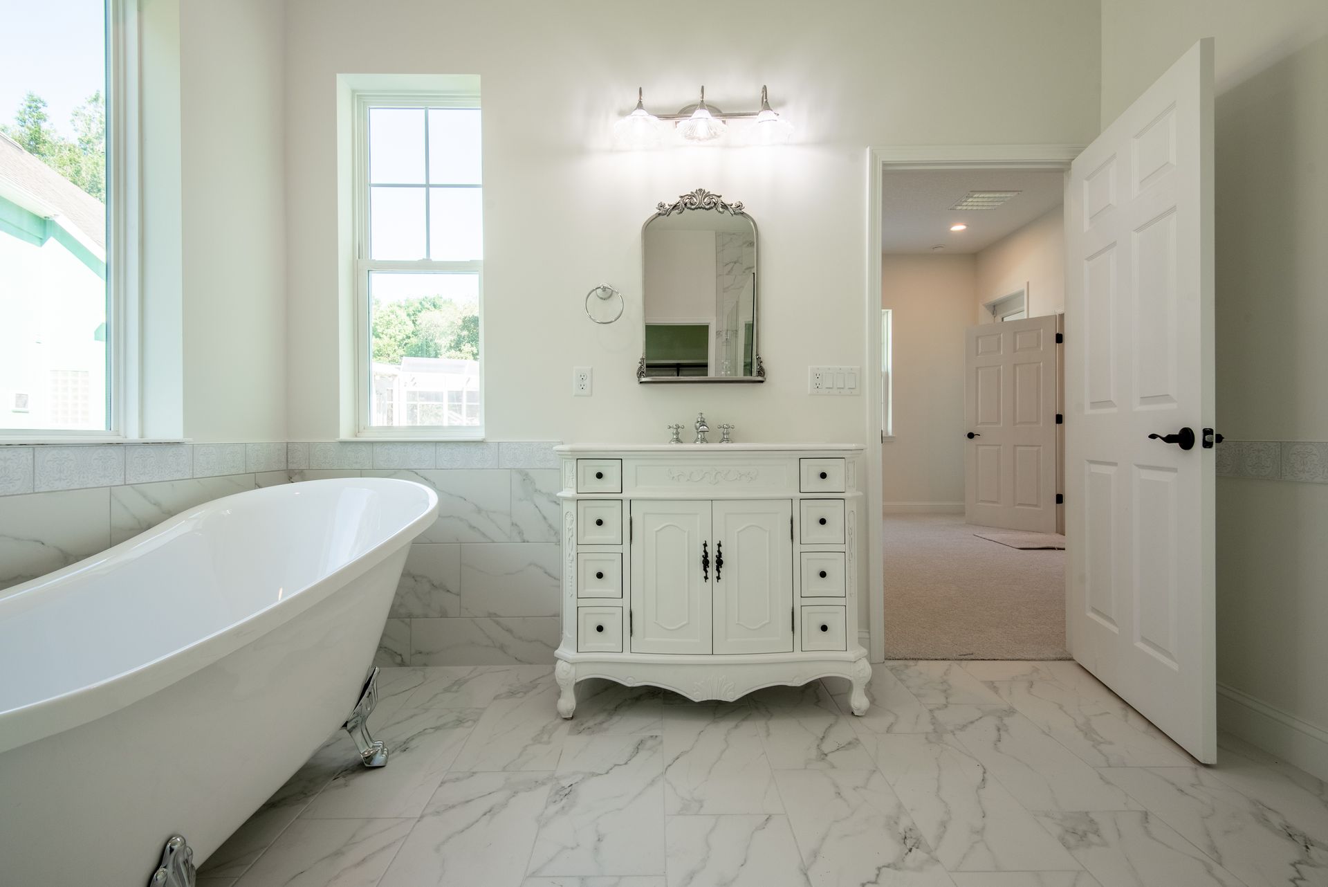 A bathroom with a bathtub , sink , mirror and window.