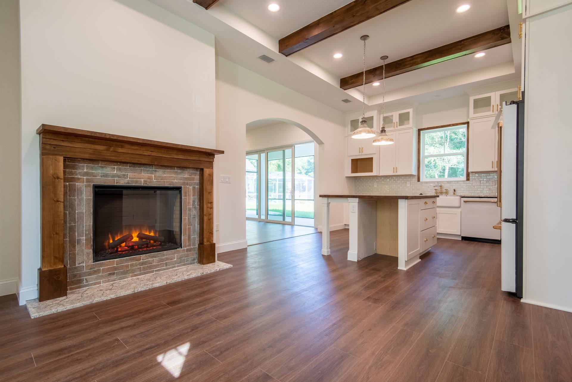 A living room with a fireplace and a kitchen in the background.