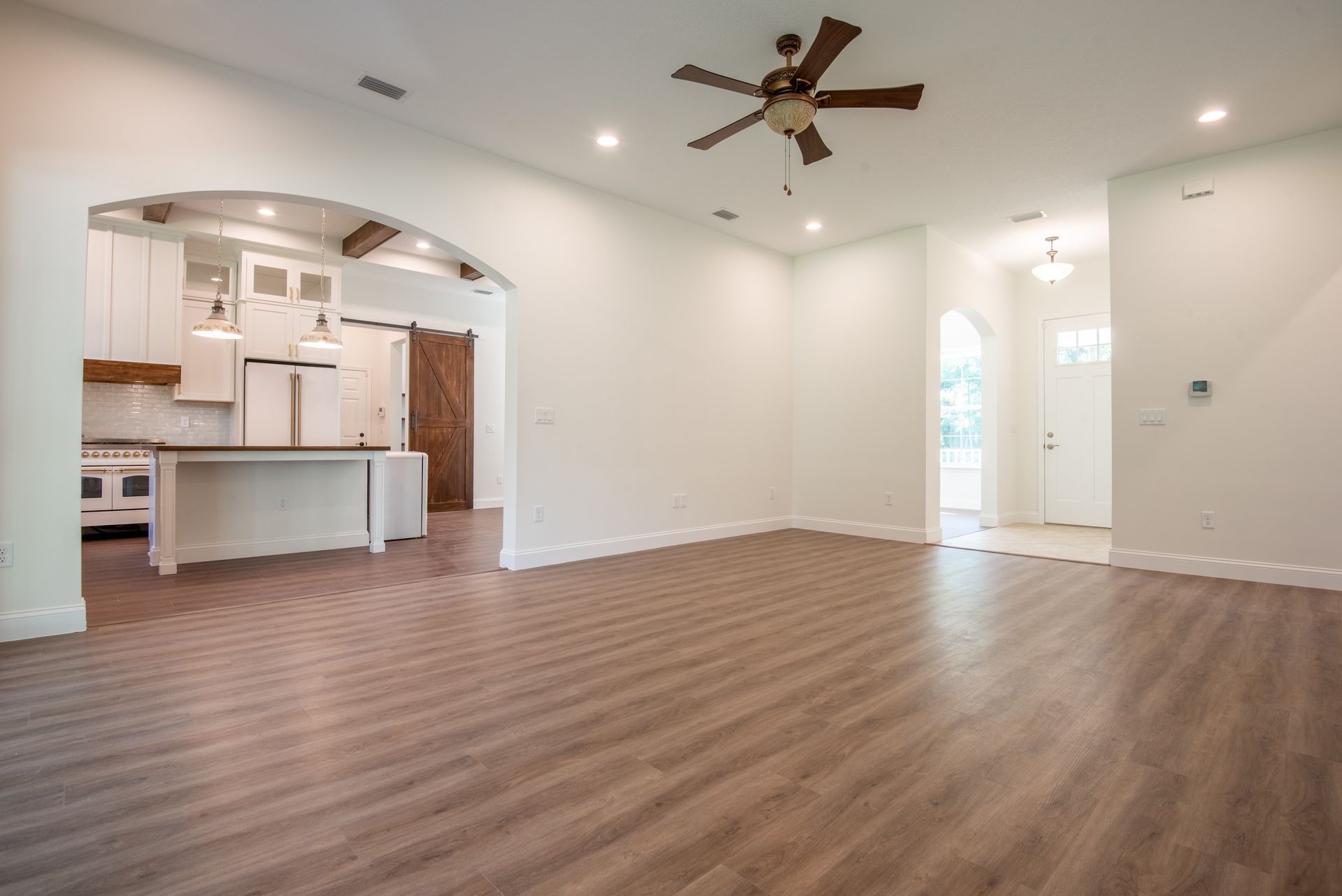 An empty living room with hardwood floors and a ceiling fan.