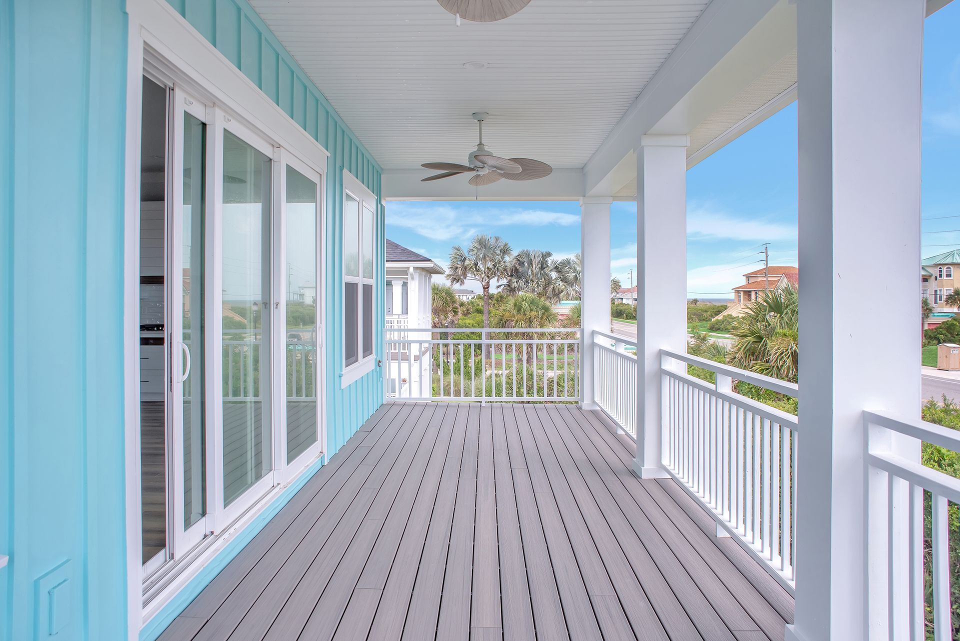 A large porch with sliding glass doors and a ceiling fan.