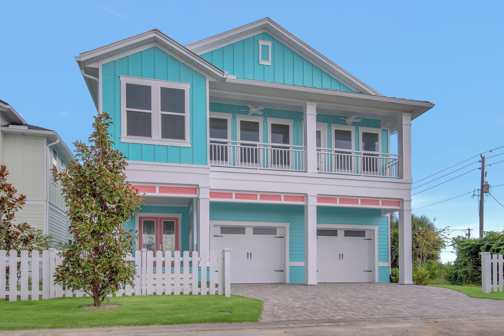A large blue house with a white fence and two garages