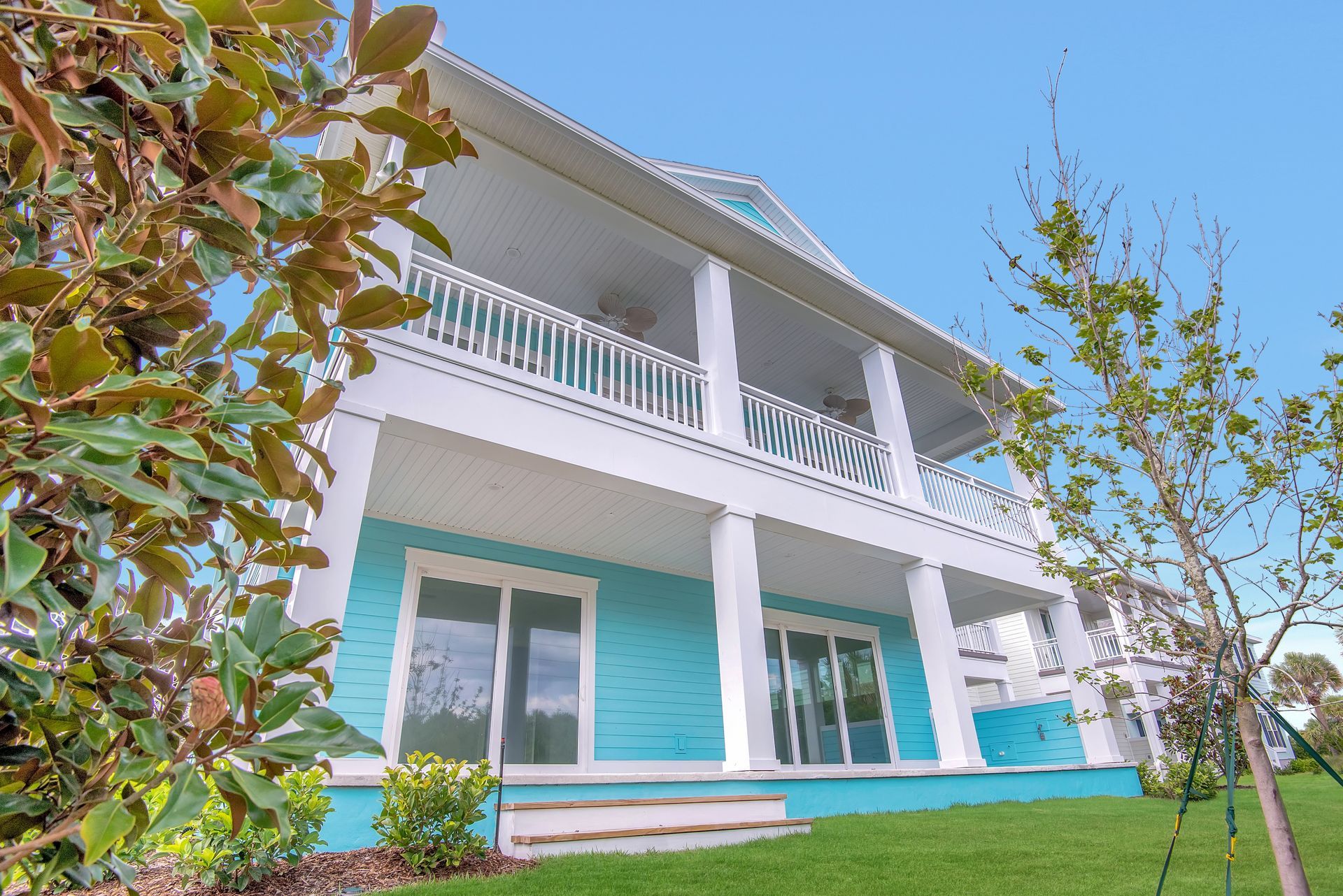A large blue and white house with a lush green lawn in front of it.