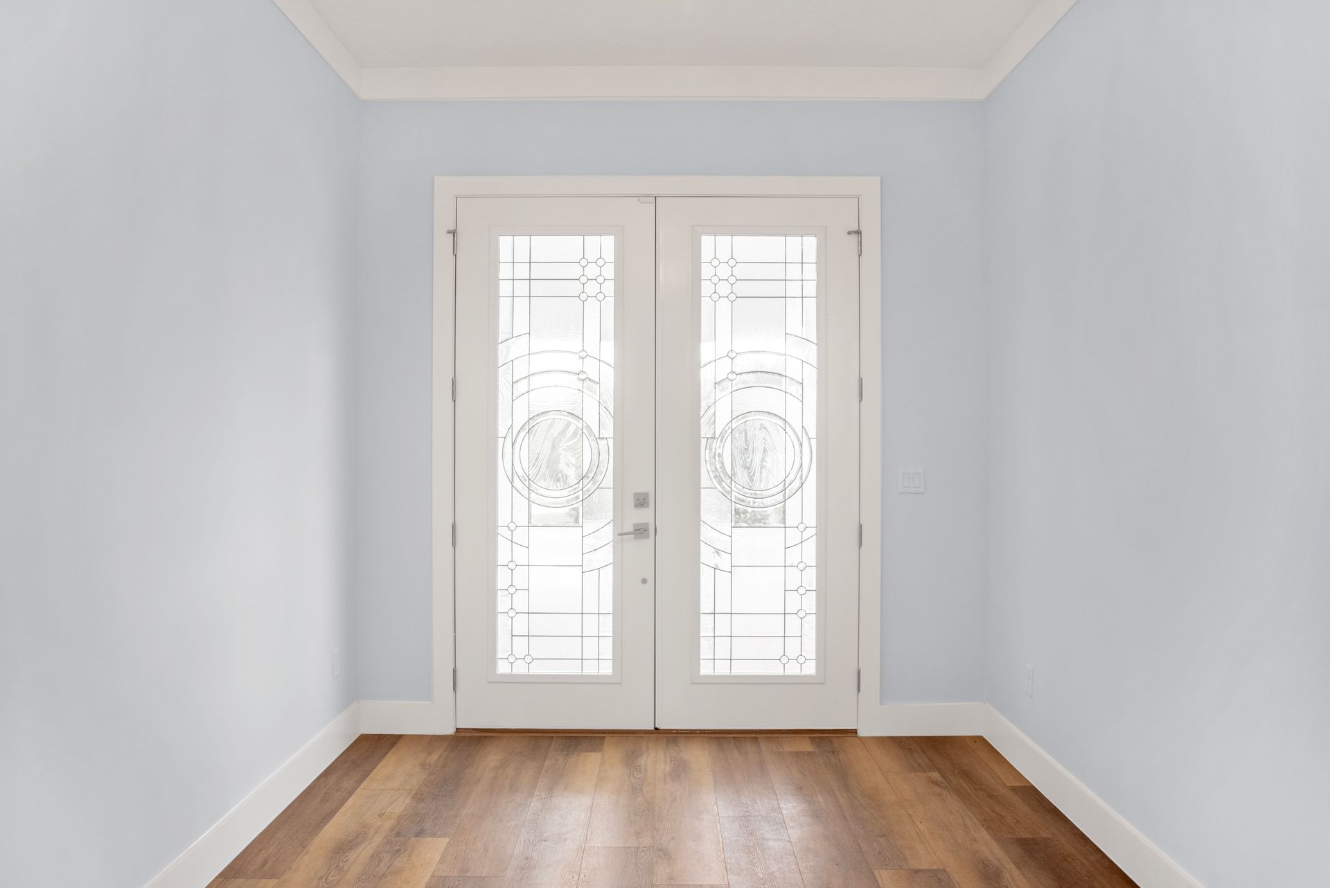 An empty room with hardwood floors and white doors