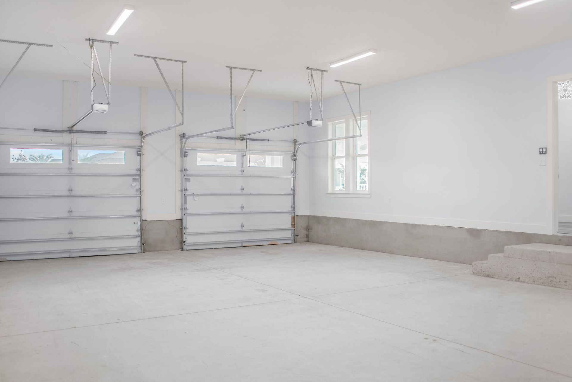 An empty garage with two garage doors and stairs.