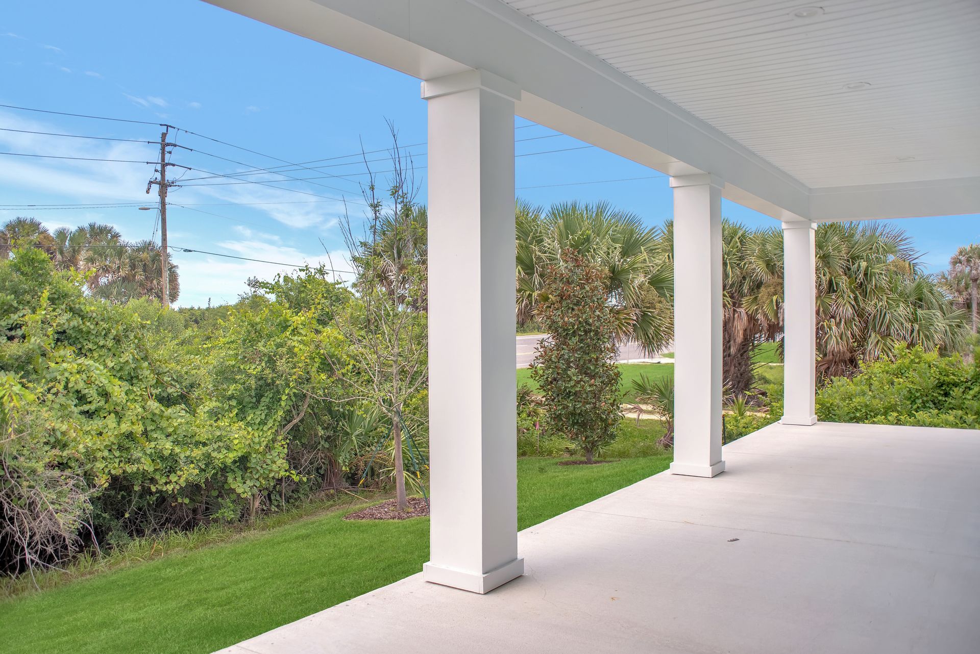A porch with columns and a view of a lush green field.