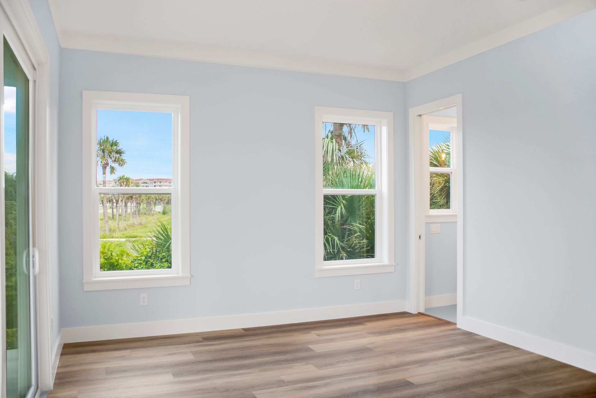 An empty room with hardwood floors and three windows.