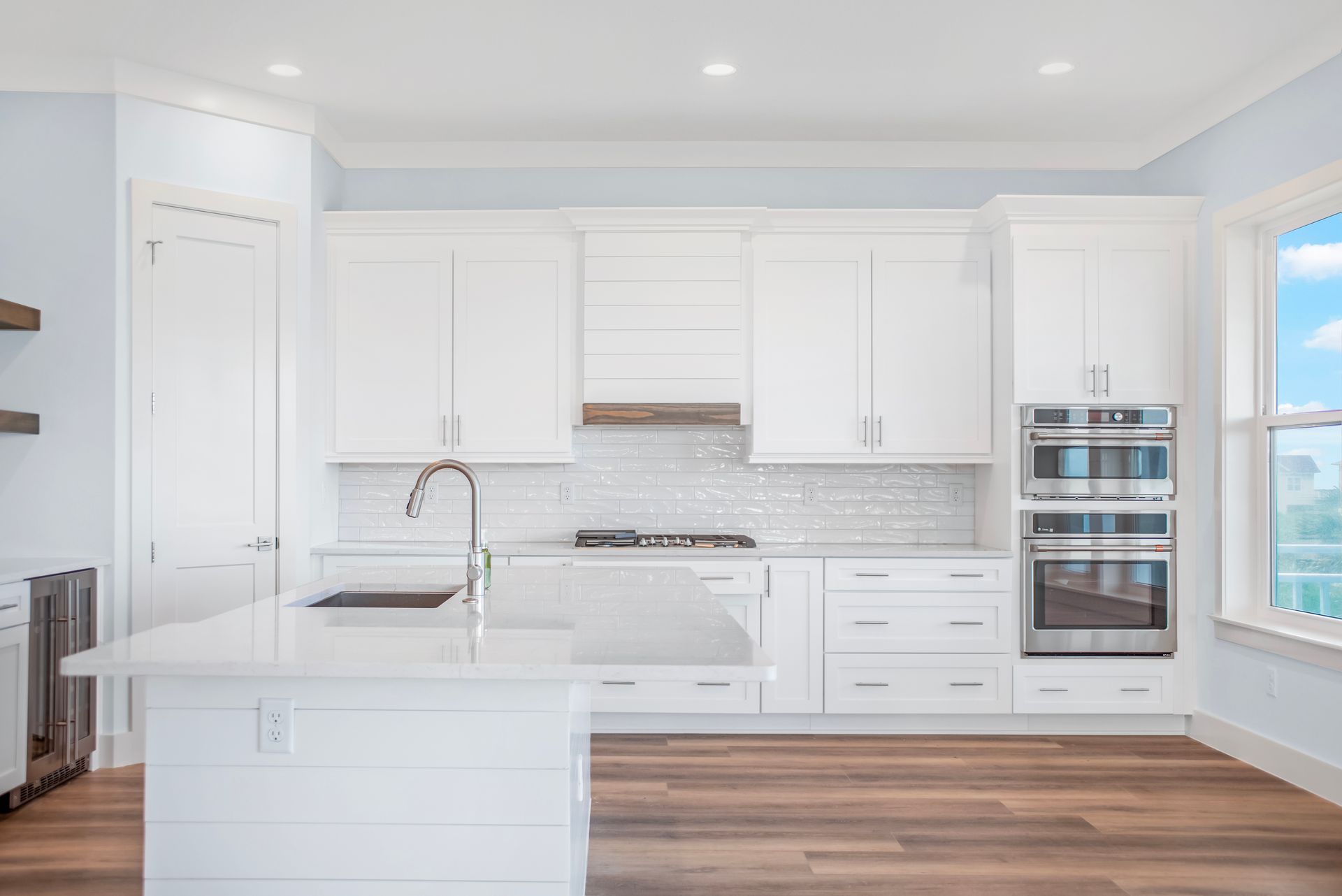 A kitchen with white cabinets , stainless steel appliances , and a large island.