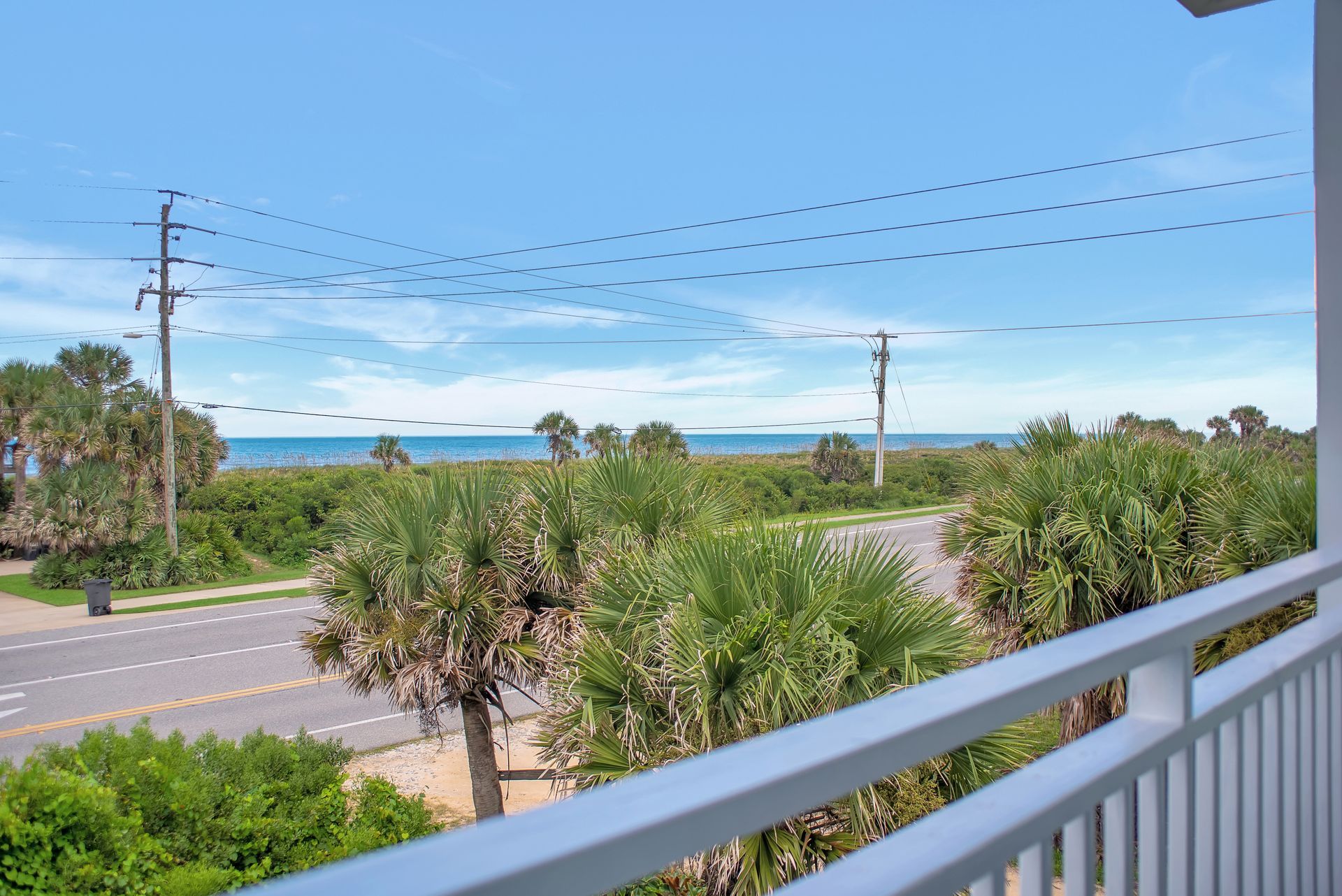 A balcony with a view of the ocean and palm trees.