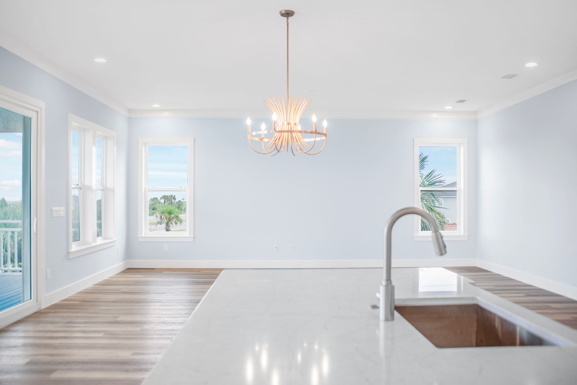 An empty kitchen with a sink and a chandelier hanging from the ceiling.