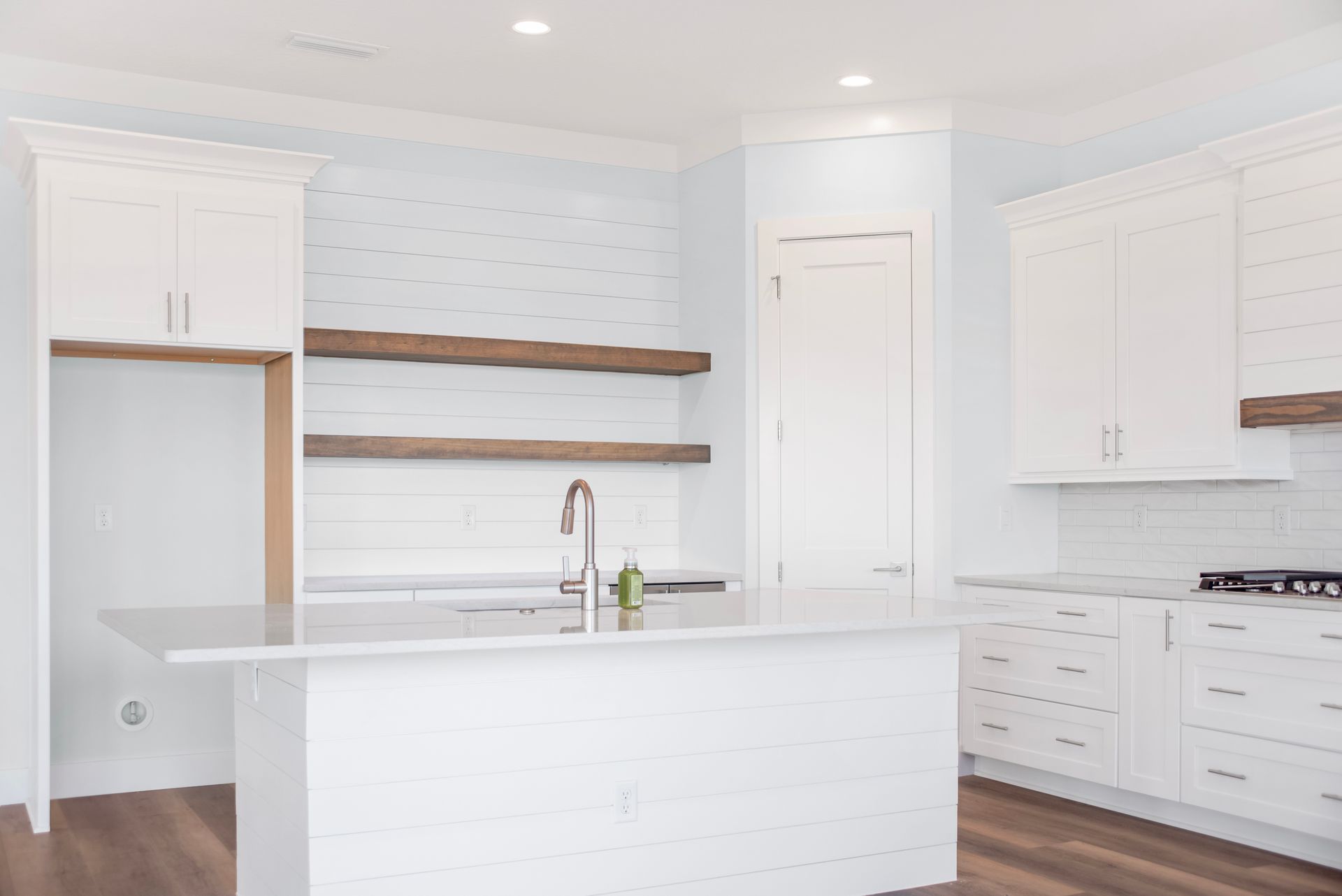 An empty kitchen with white cabinets and a large island.