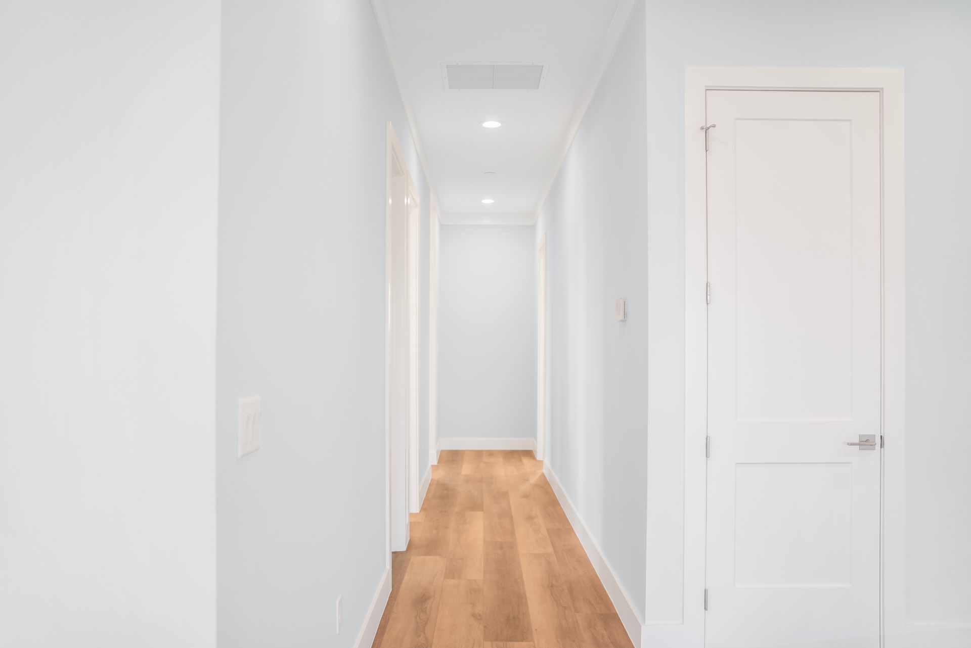 A long hallway with white walls and wooden floors.