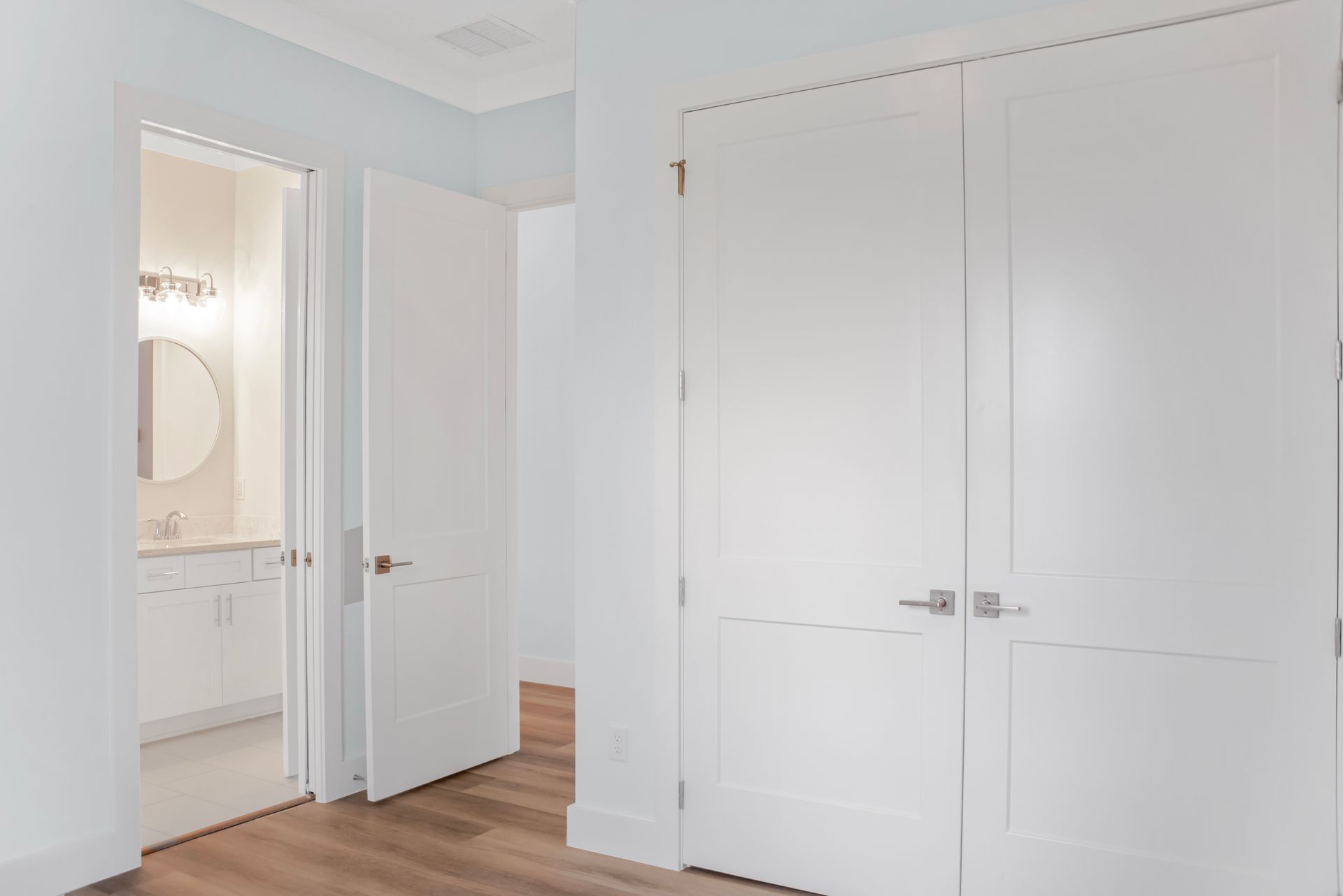 A hallway in a house with white doors and a bathroom.