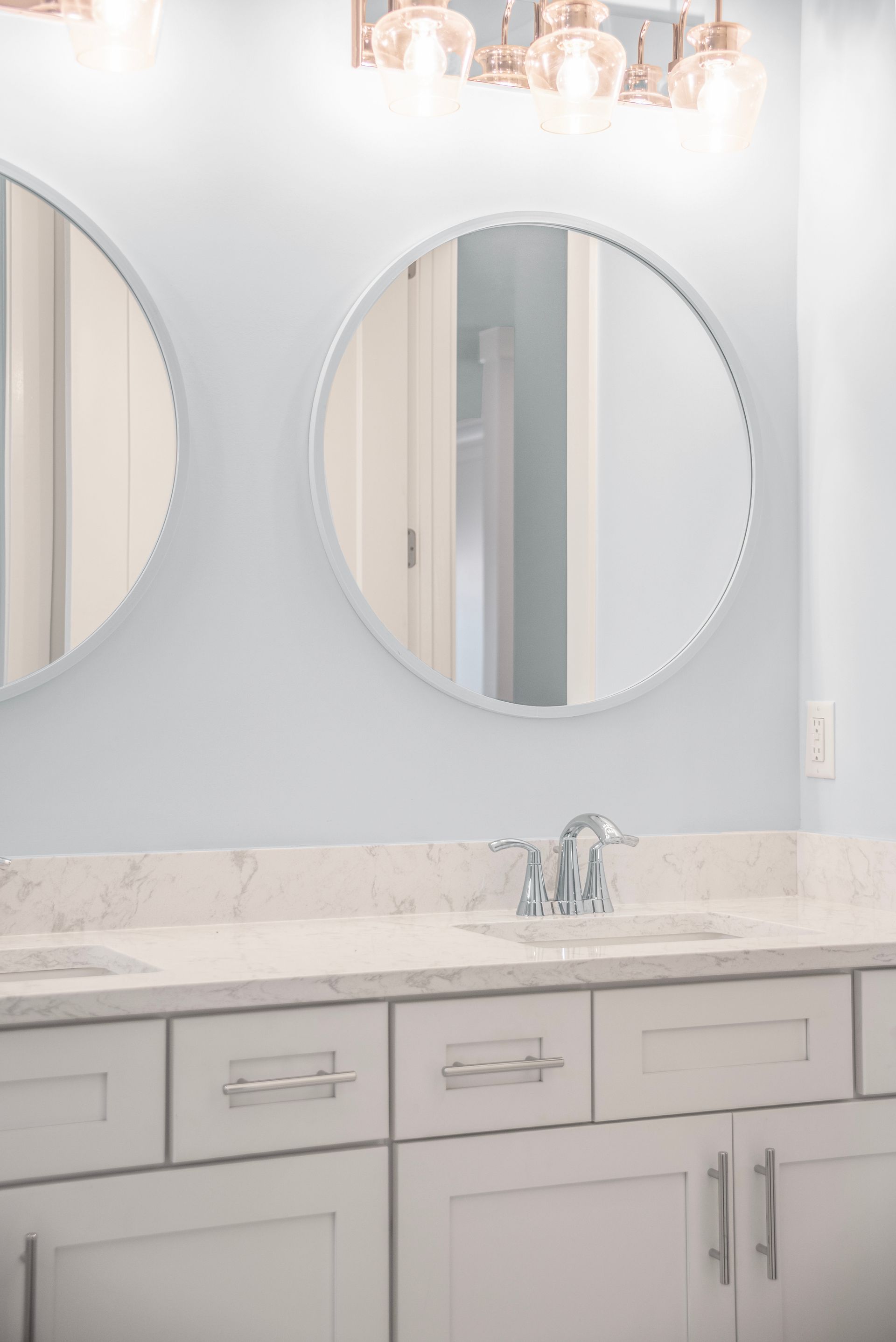 A bathroom with two sinks and two round mirrors.