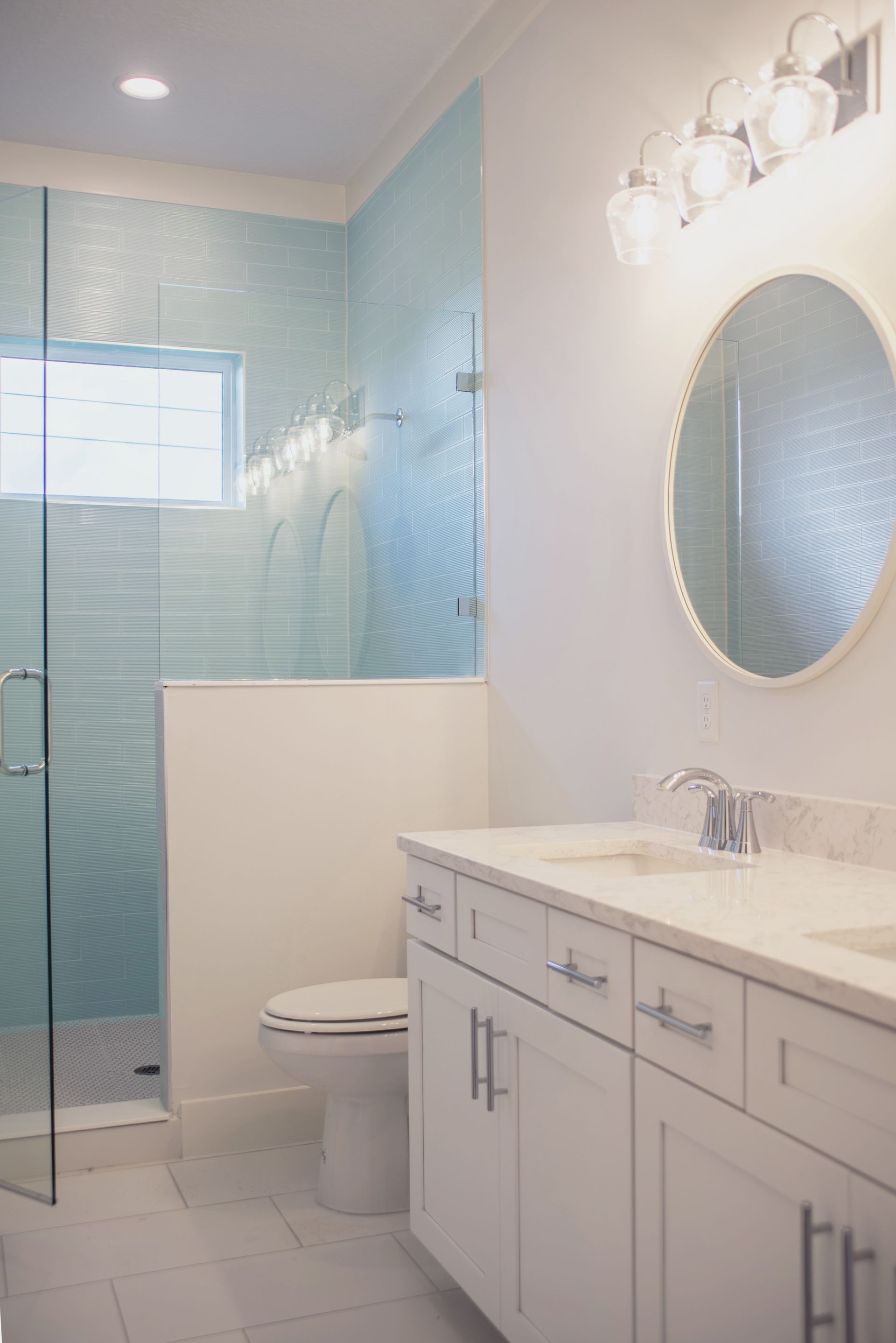 A bathroom with a toilet , sink , mirror and shower.