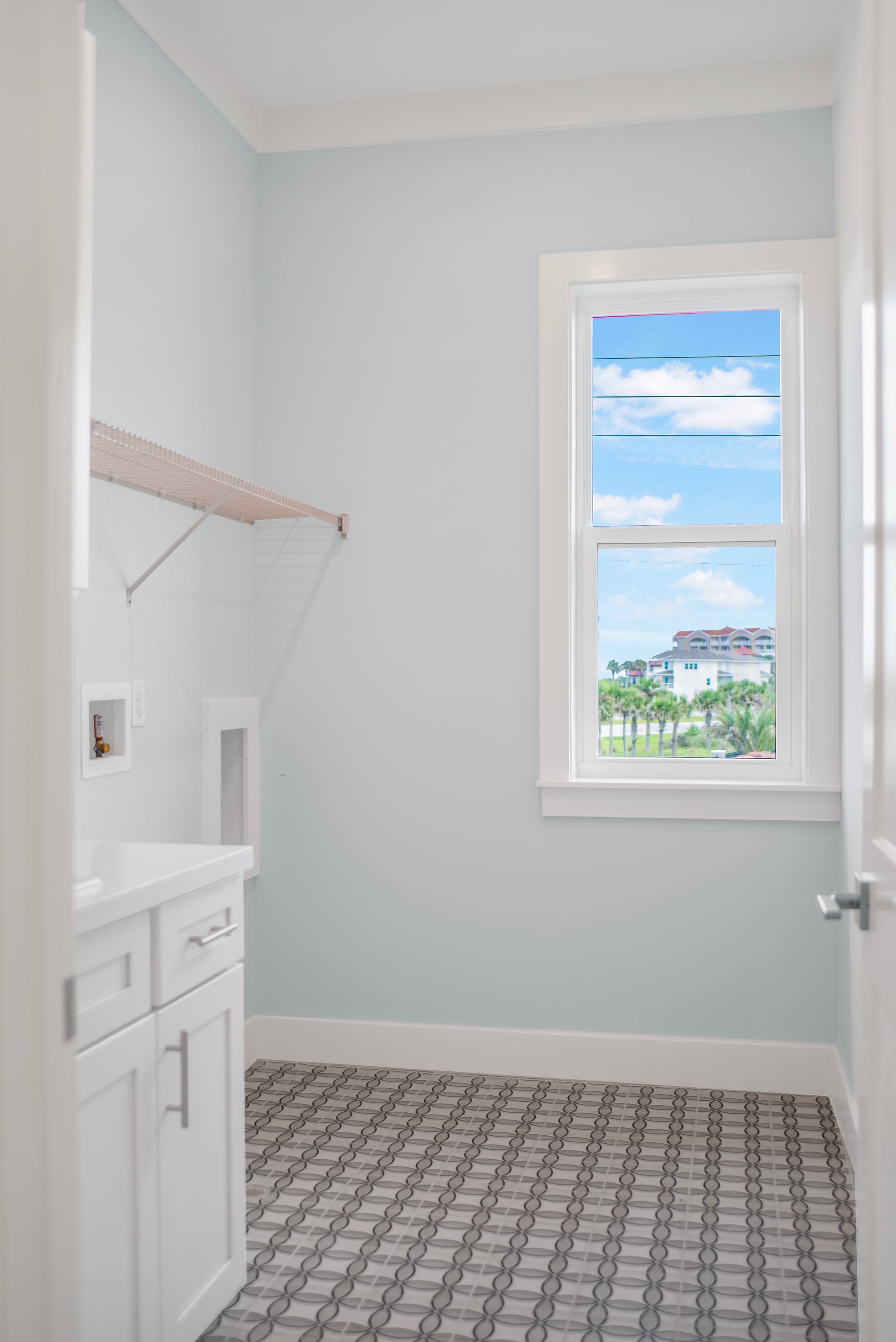 A laundry room with blue walls and a window.