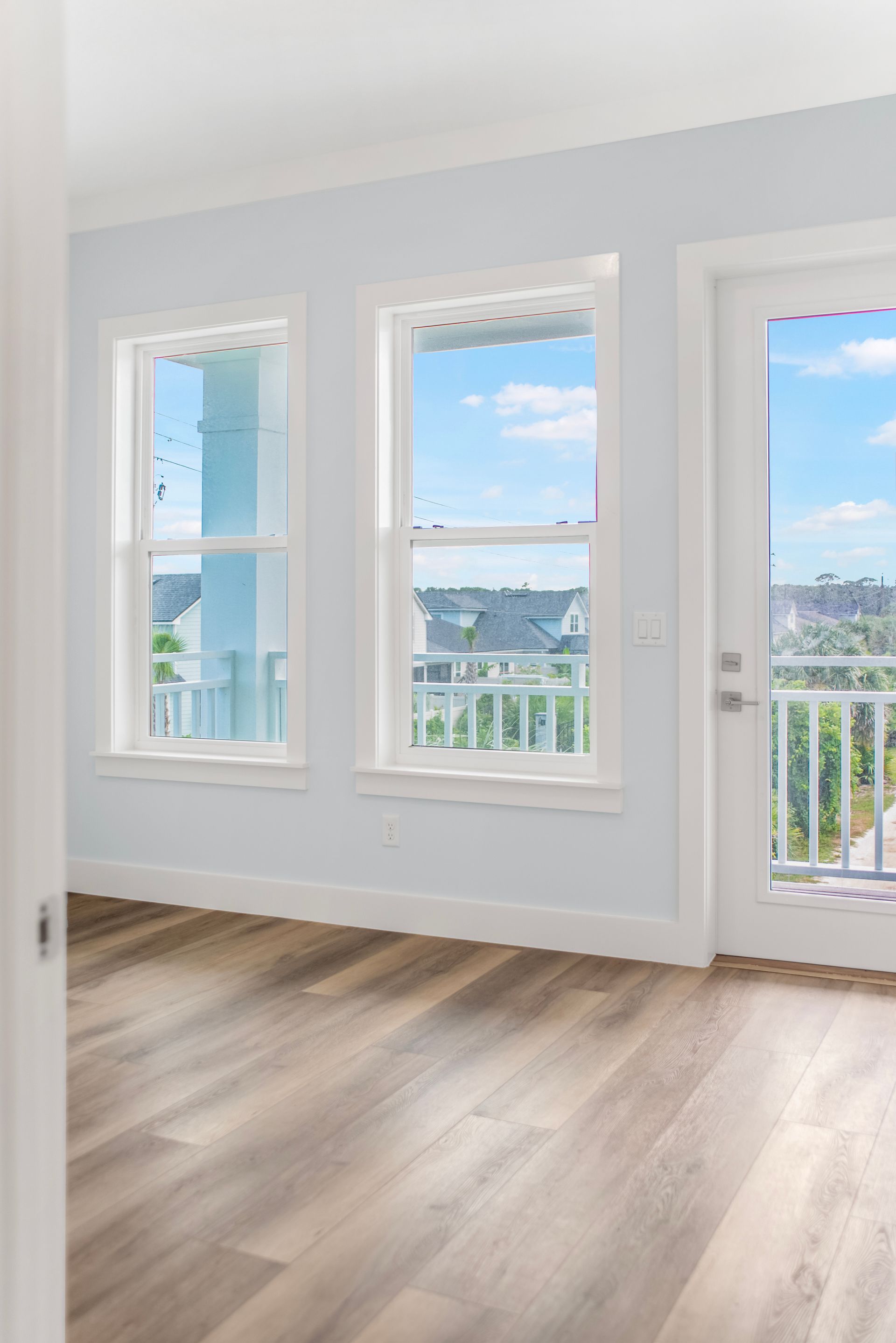 An empty room with hardwood floors and a balcony with a view of the ocean.
