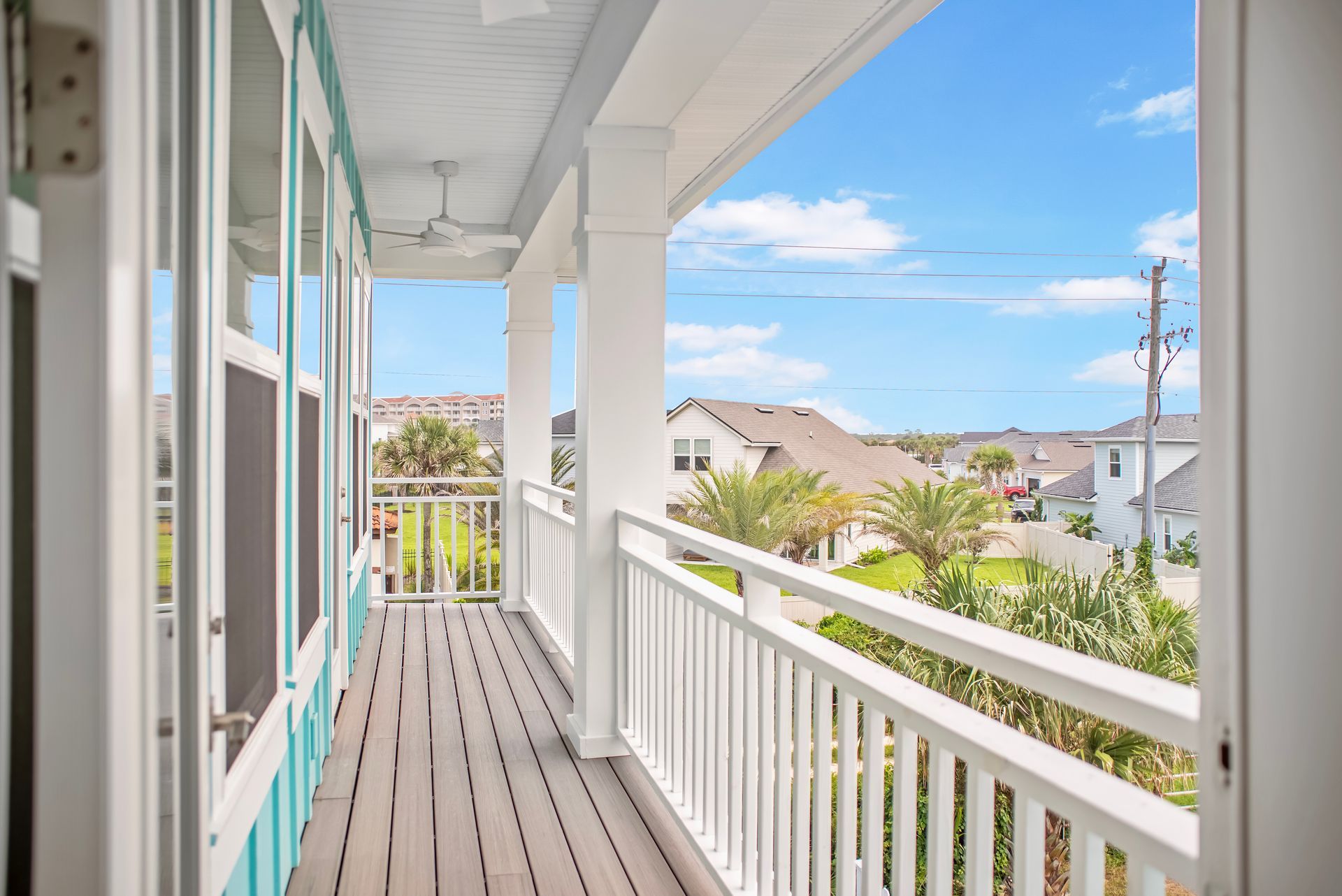 A balcony with a white railing and a view of a house.