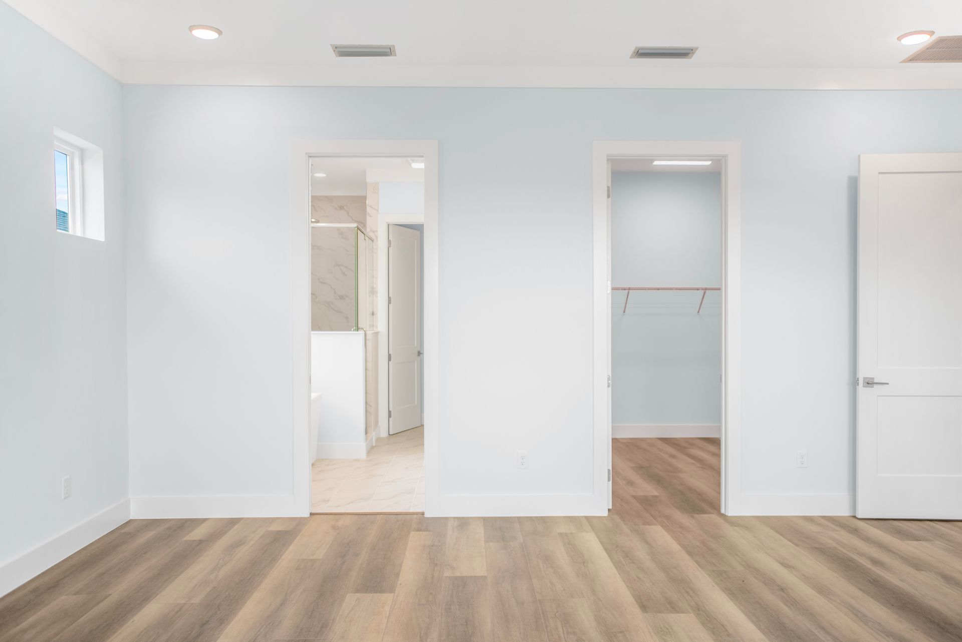 An empty room with hardwood floors , white walls , and a walk in closet.