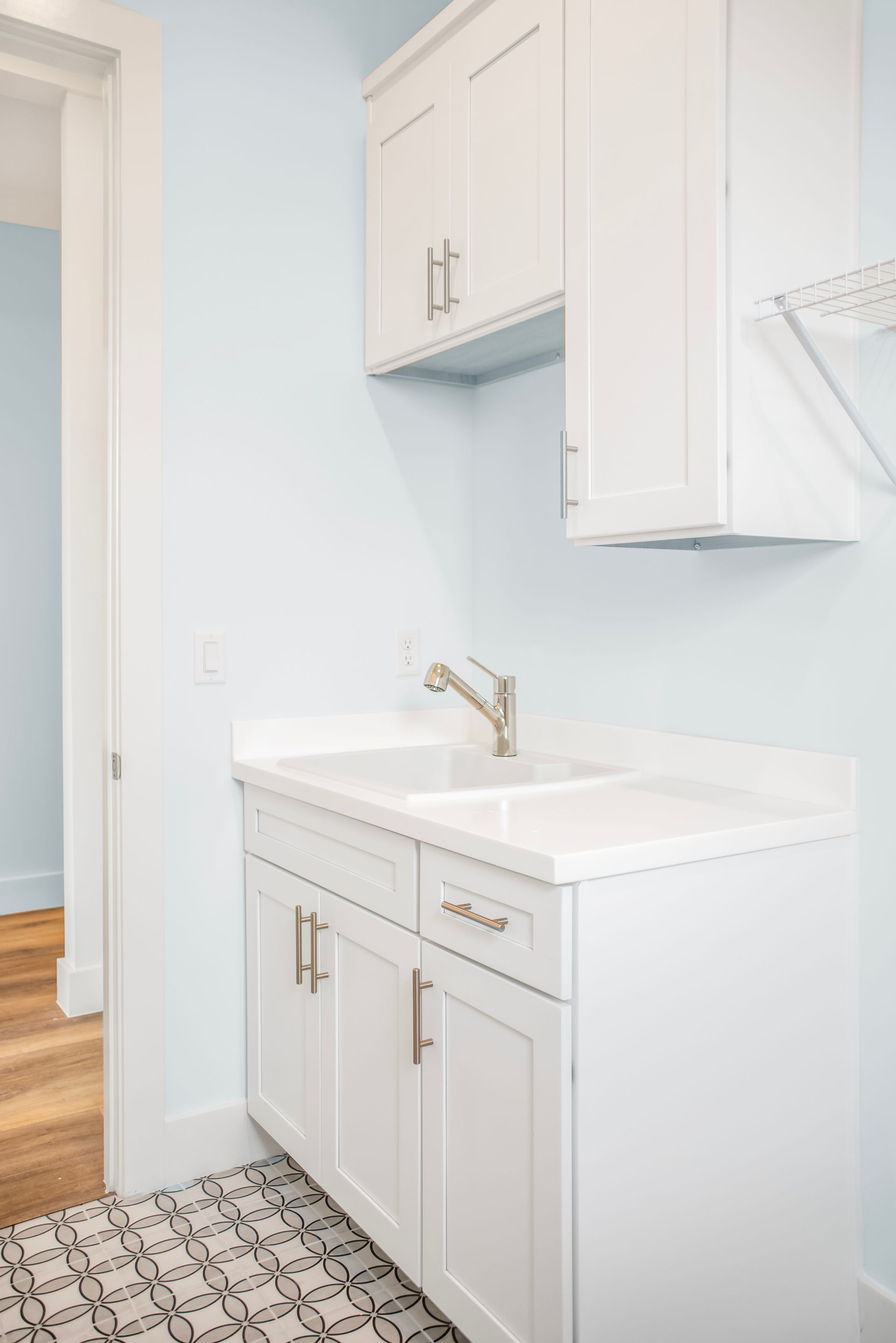 A laundry room with white cabinets and a sink.