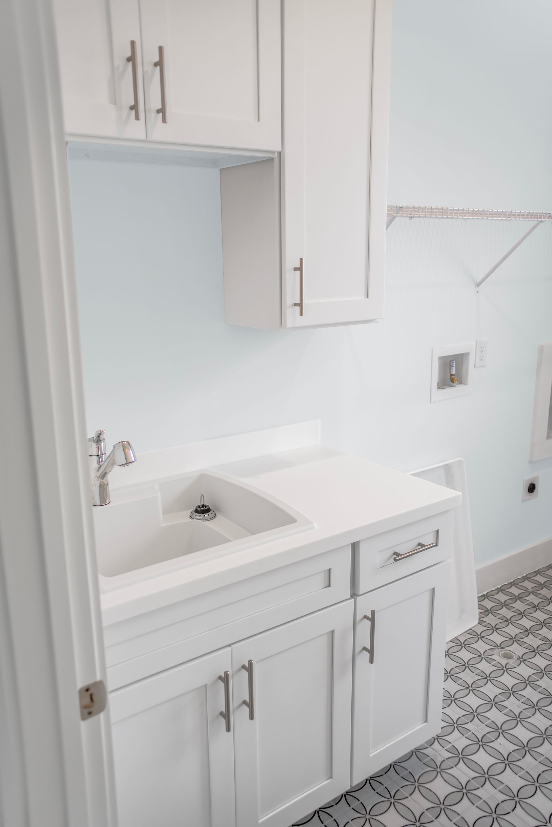 A laundry room with white cabinets and a sink.