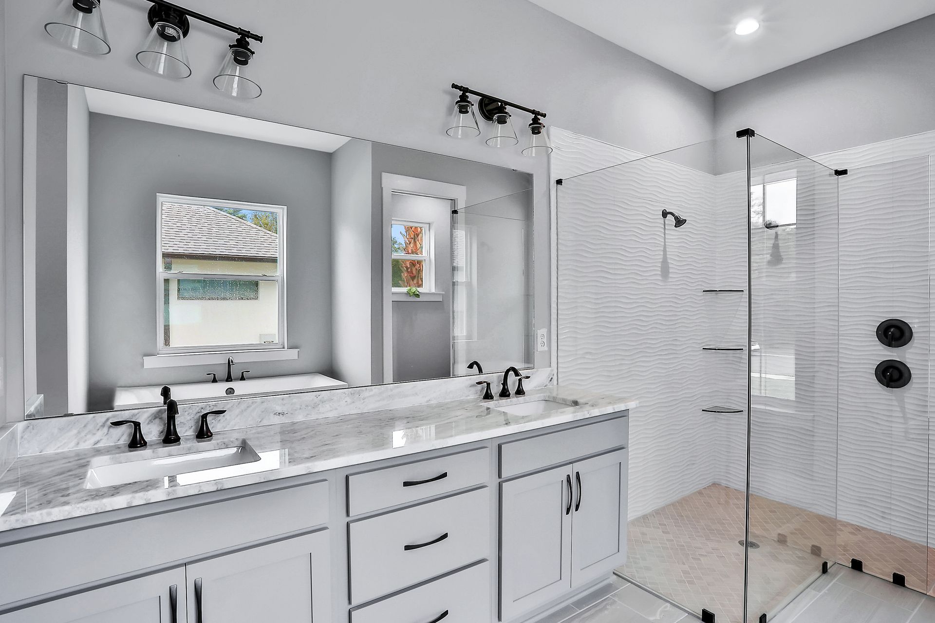 A bathroom with two sinks and a walk in shower.